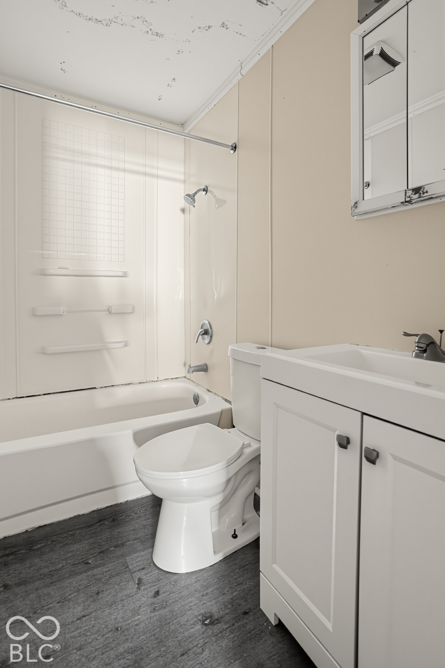 Bathroom featuring a white vanity cabinet, wood-finish flooring, a wall-mounted mirrored medicine cabinet, and a bathtub with an integrated shower surround