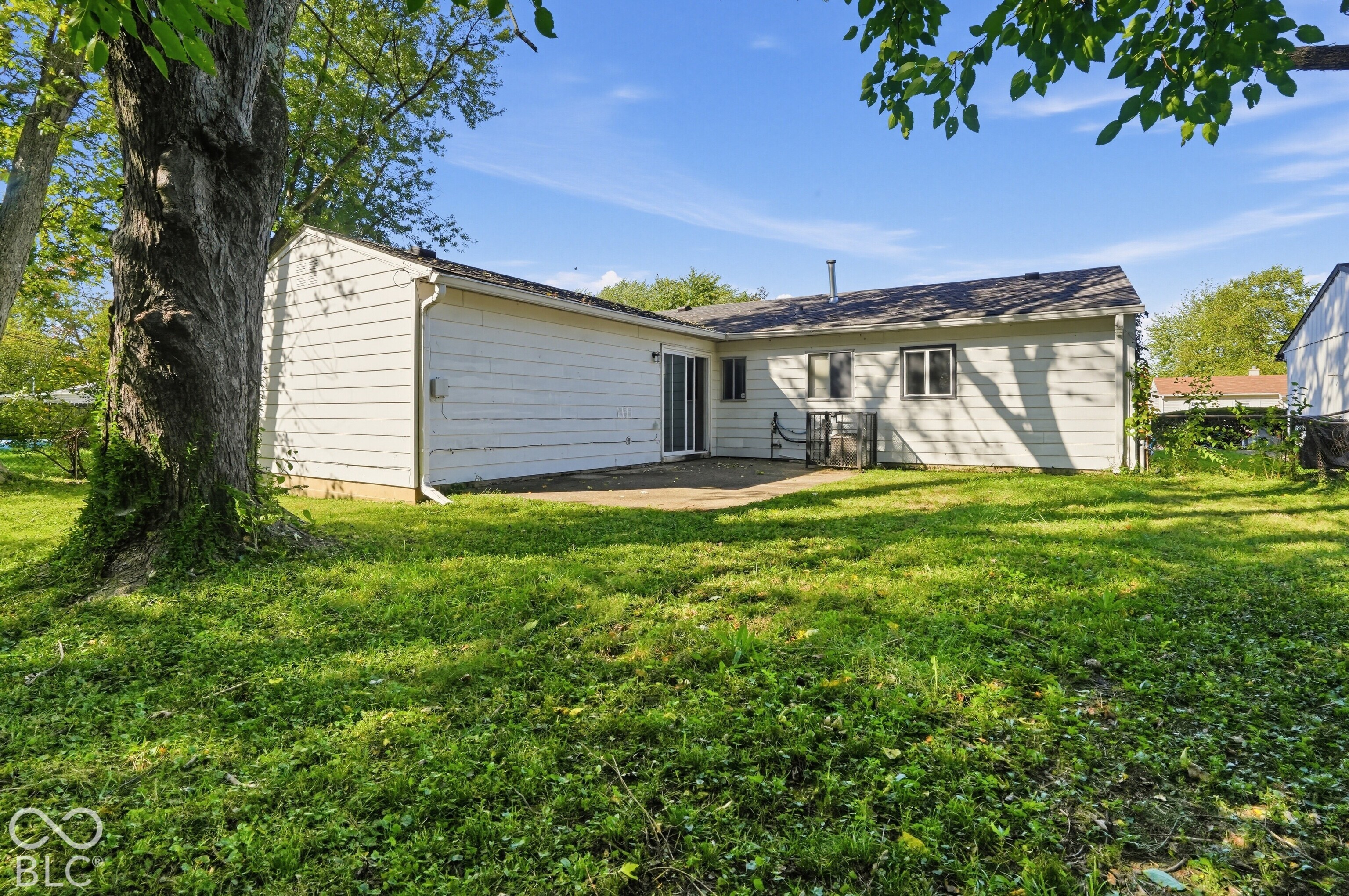 Exterior featuring horizontal siding, concrete patio, sliding glass door, and mature trees