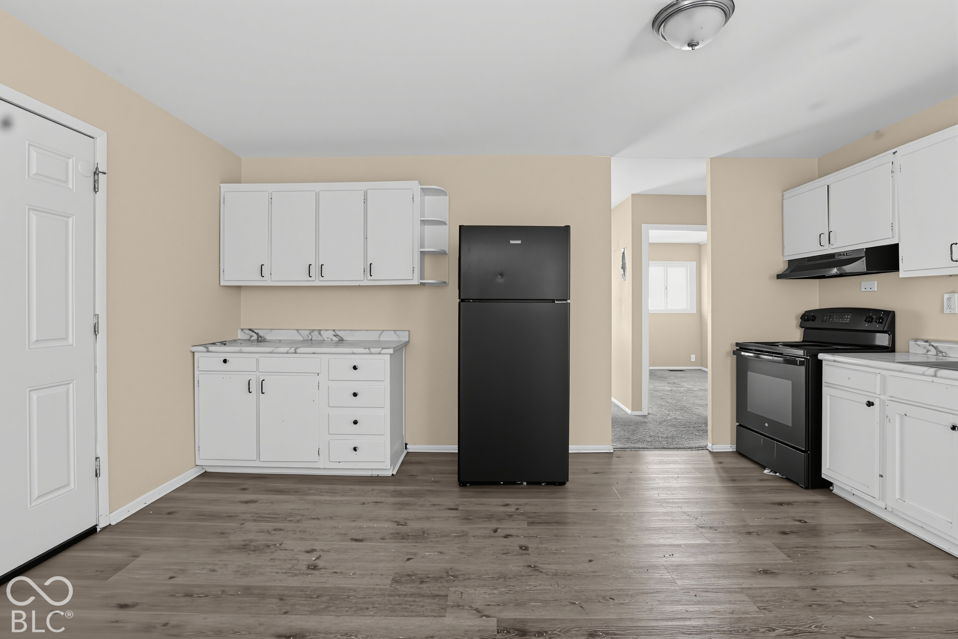 Kitchen featuring wood-finish flooring, white cabinetry, stone-patterned countertops, and a black refrigerator and stove