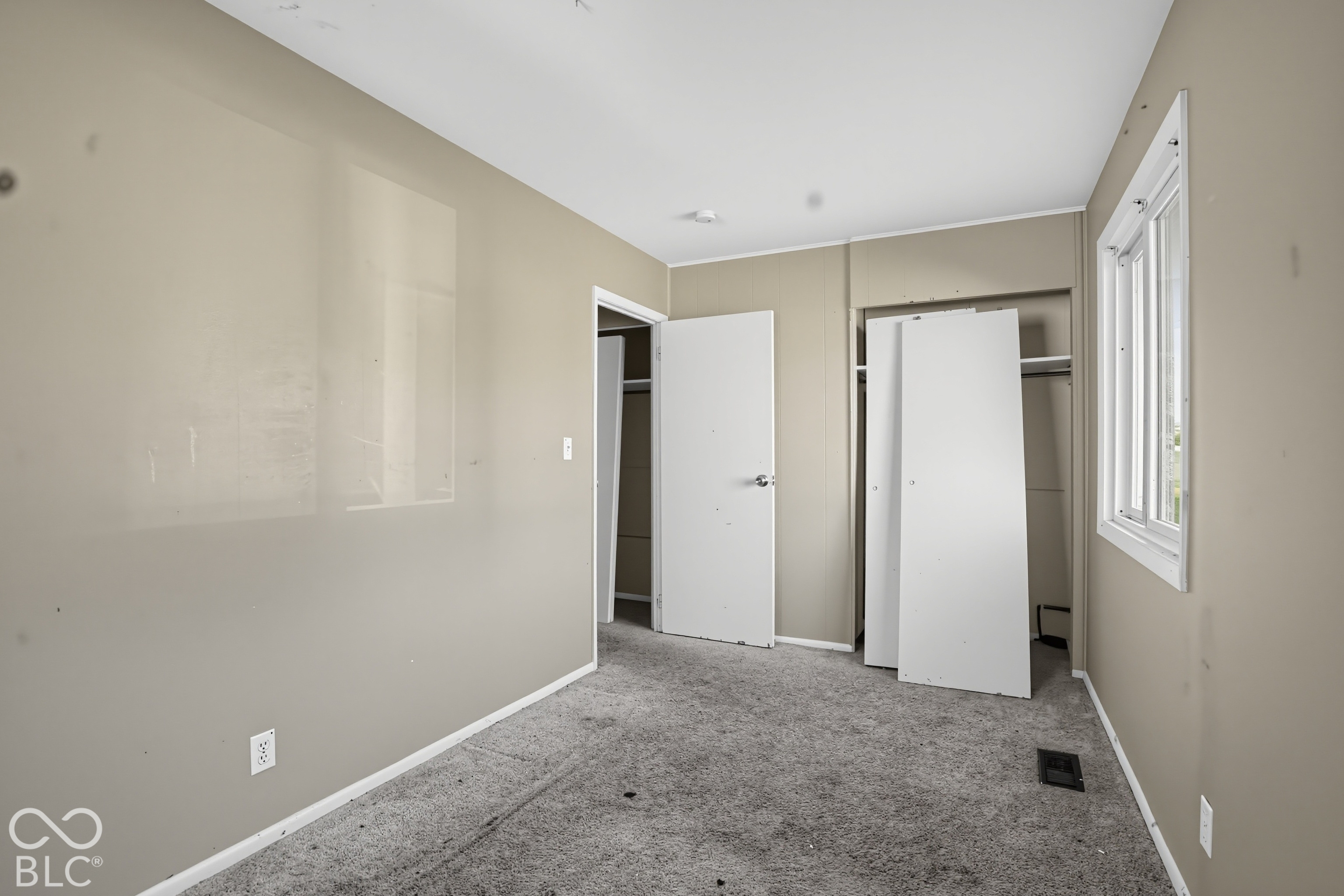 Interior room featuring neutral wall paint, carpeted flooring, a closet with shelving, and a double-pane window