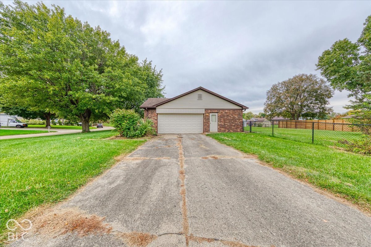Detached garage with brick masonry and siding exterior, concrete driveway, and chain-link fenced perimeter
