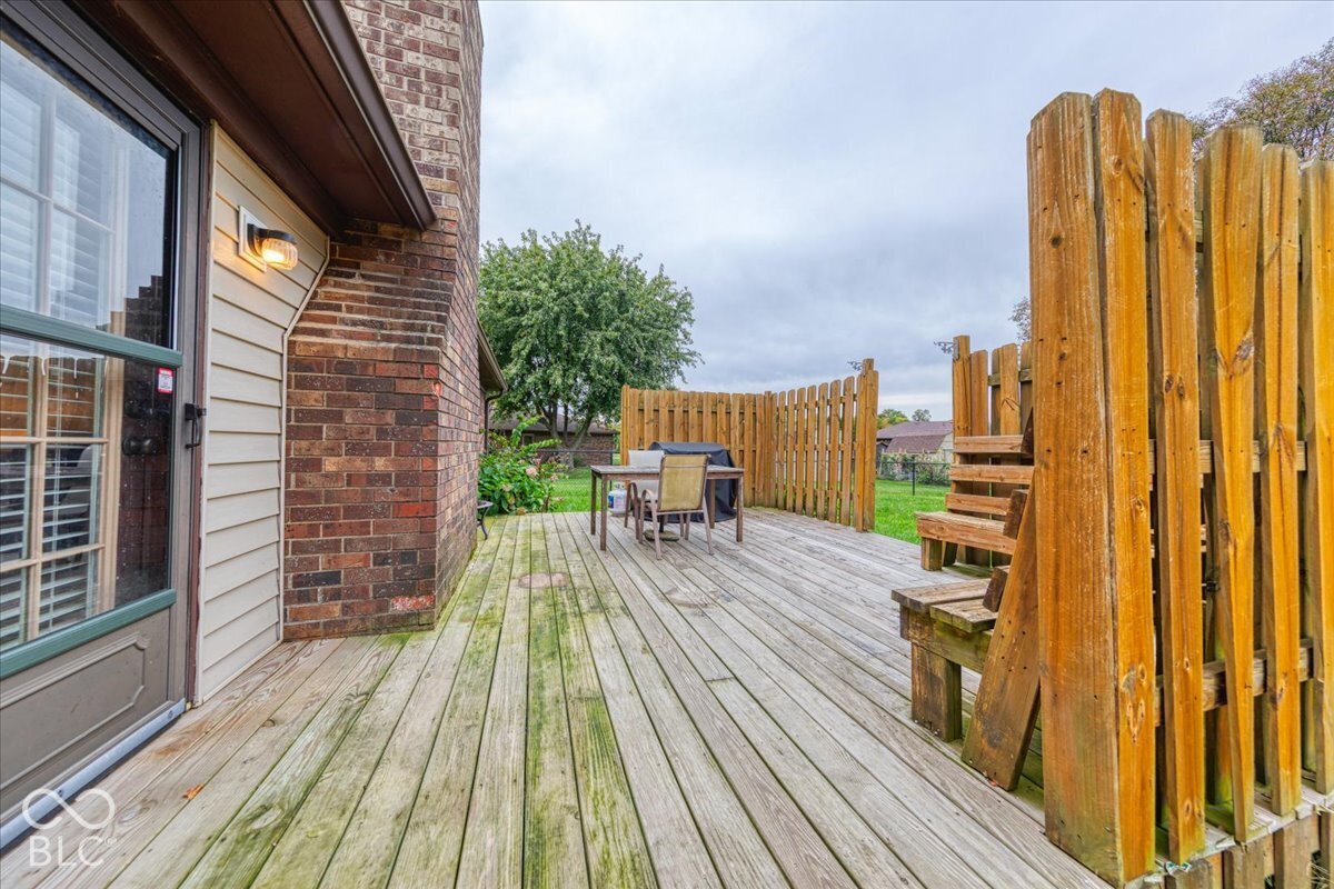 Exterior wood decking featuring built-in bench seating, vertical wood privacy screening, and brick chimney siding