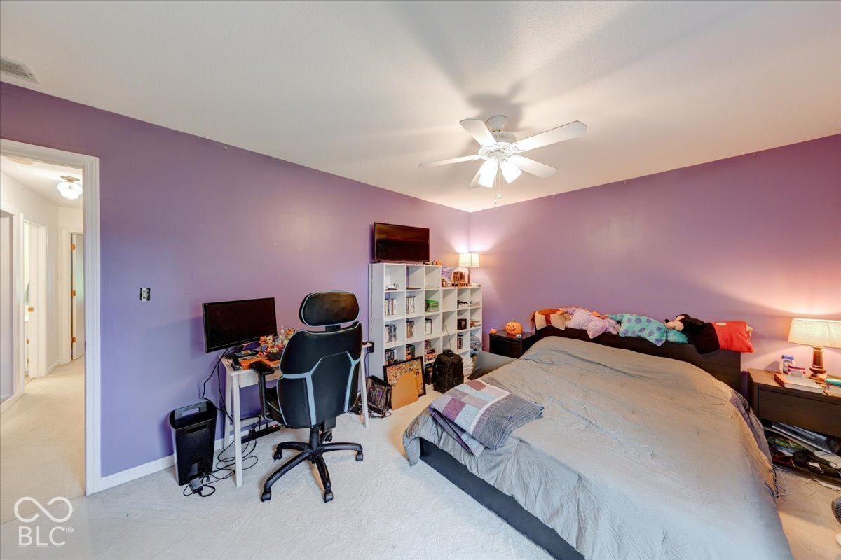 Spacious room featuring neutral carpeting and a white multi-blade ceiling fan