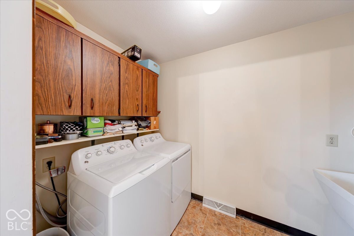 Laundry space featuring wood-finish cabinetry, an open built-in shelf, and a utility sink