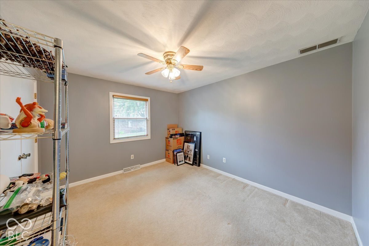 Neutral wall finishes, carpeting, and a ceiling fan with integrated lighting