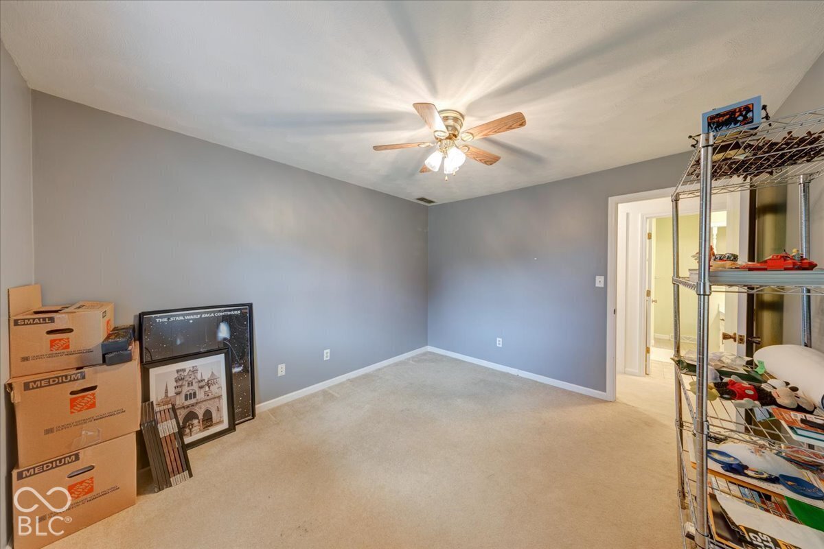 Neutral-toned interior room featuring wall-to-wall carpeting and a central ceiling fan with integrated lighting