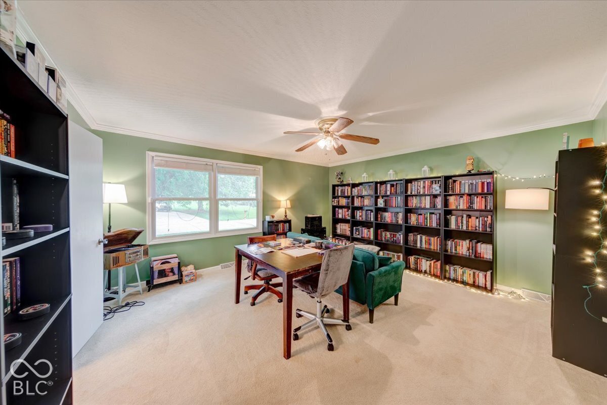 Expansive room featuring wall-to-wall carpeting, large windows, a ceiling fan with integrated light fixture,