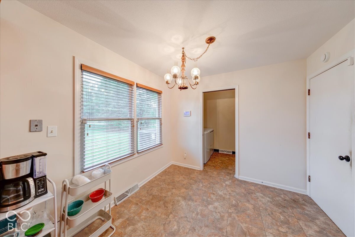 Multi-light chandelier, dual windows with horizontal blinds, and resilient tile-finish flooring