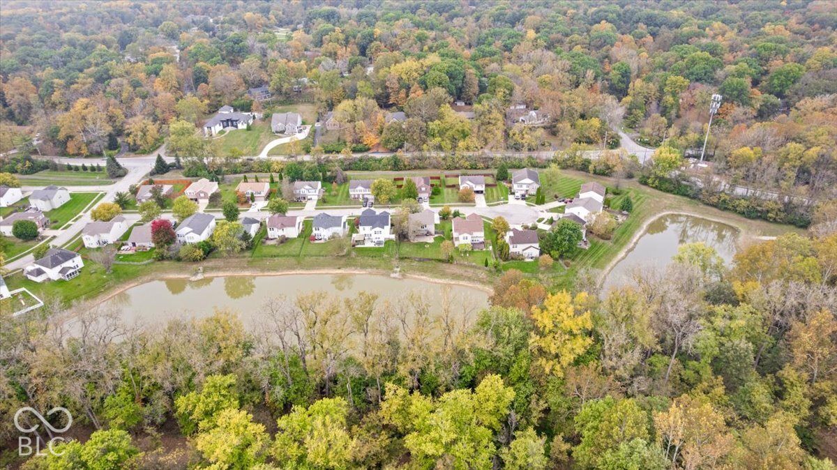 Aerial perspective featuring bodies of water, mature tree canopy, and established neighborhood landscaping