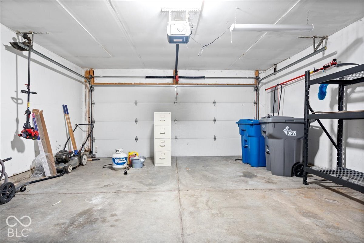 Attached multi-car garage featuring a concrete floor, motorized sectional garage door, and ceiling-mounted electrical lighting