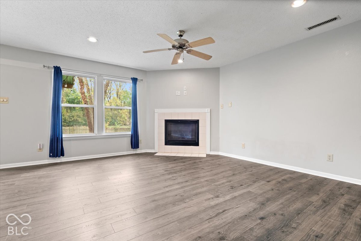 Wood-finish flooring, fireplace with a tile surround, ceiling fan, and recessed lighting