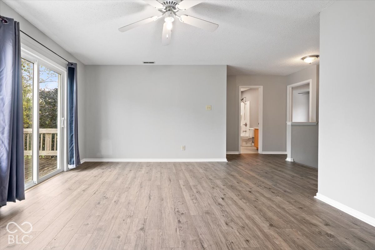 Living area featuring wood-finish flooring, a ceiling fan, and sliding glass doors