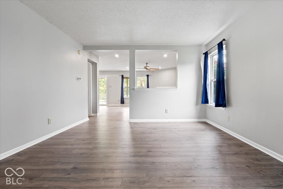 Interior space featuring wood-finish flooring, neutral wall paint, recessed lighting, and a pass-through wall opening