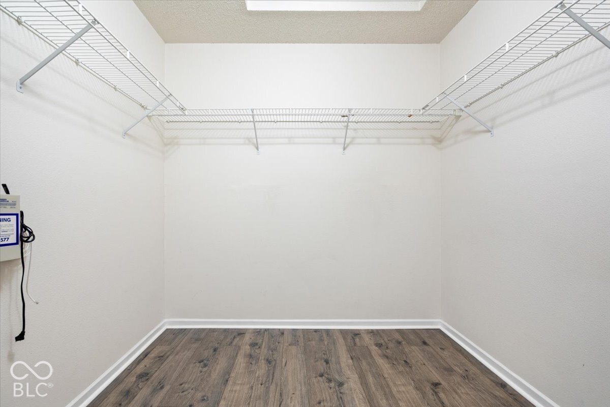 Storage area featuring wood-finish flooring and multi-tiered white wire shelving
