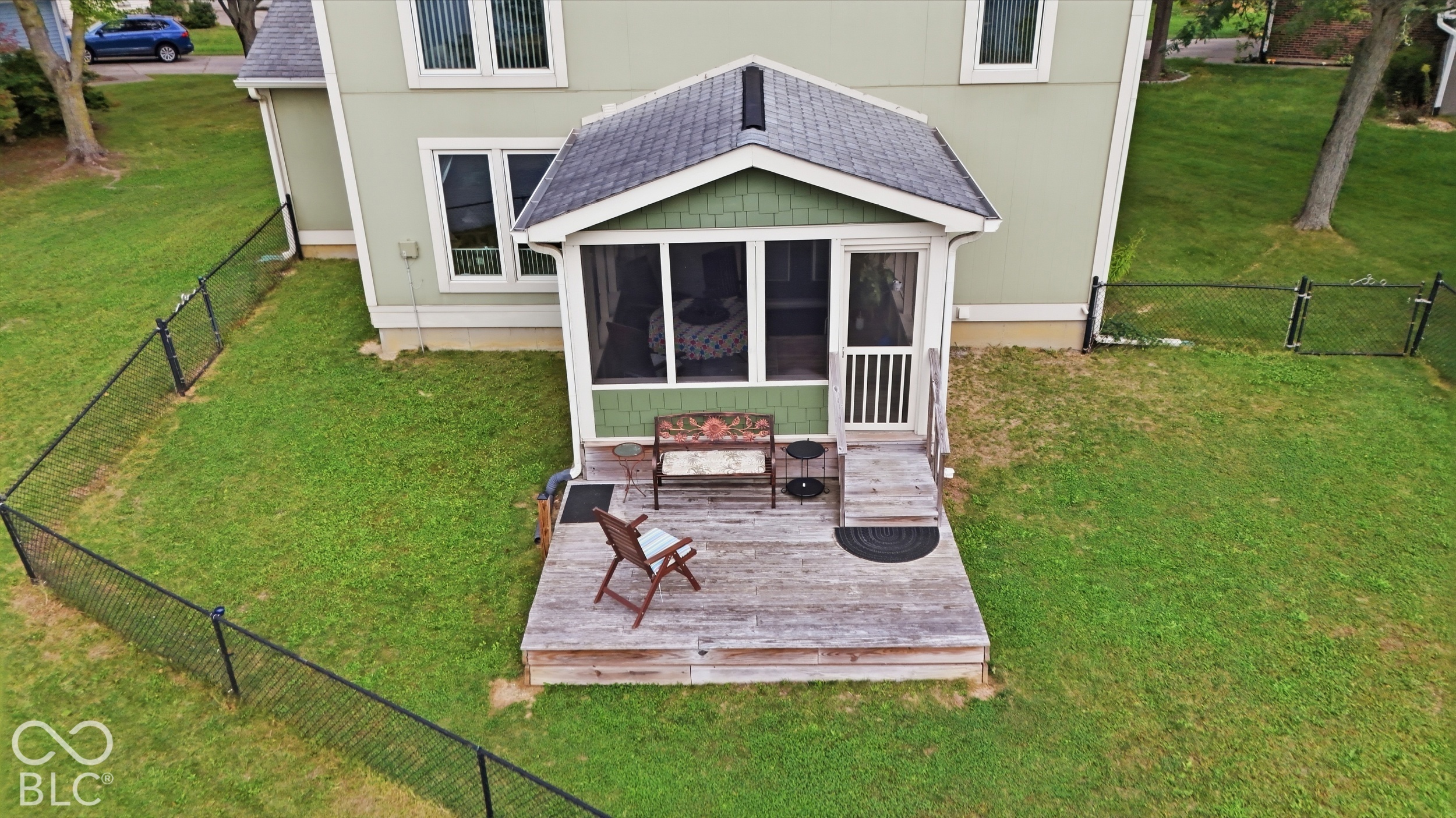 Screened porch with a gable roof, wood-plank deck, and a fenced backyard