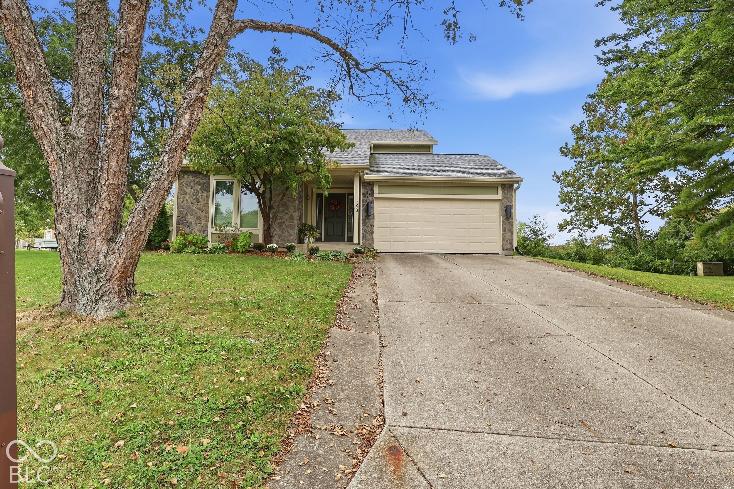 Exterior facade featuring stone veneer detailing, covered entryway, concrete driveway, and attached garage