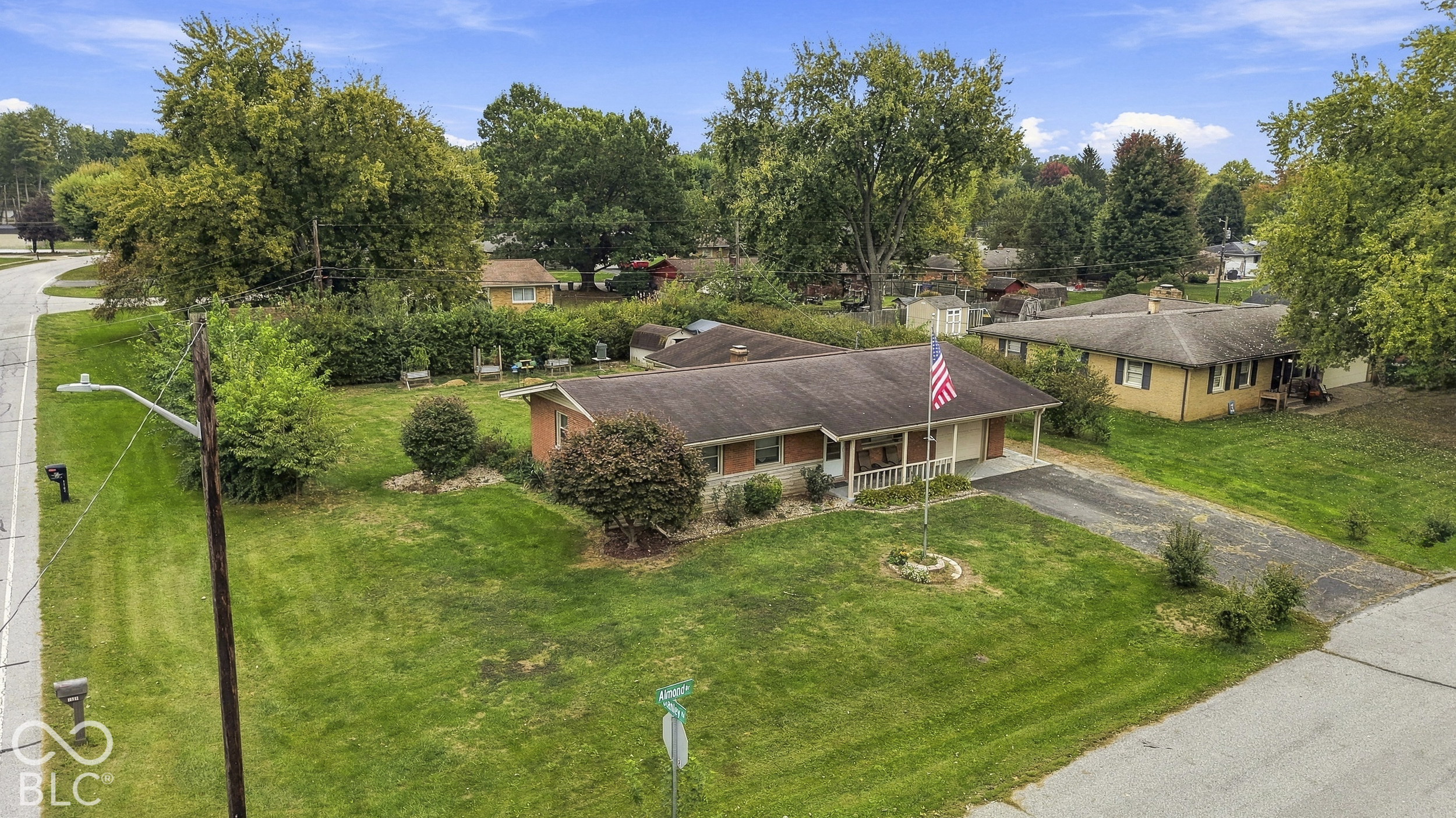 Ranch-style residence featuring a brick and siding exterior, an attached carport, and a paved driveway situated on a spacious corner lot with mature landscaping