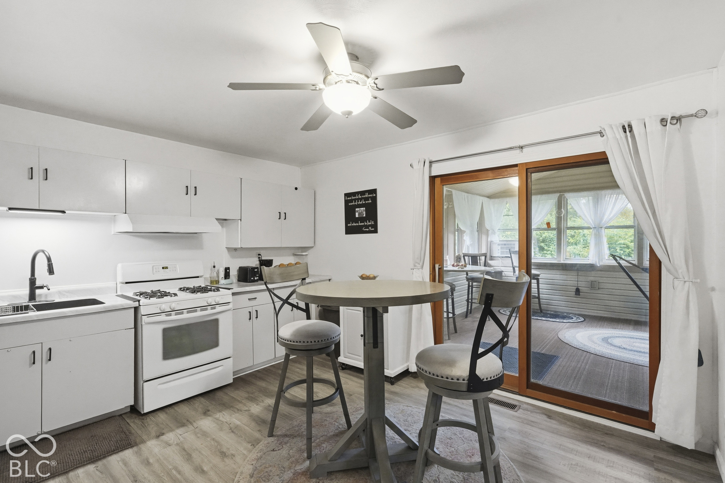 Another view of the kitchen. It has a nice ceiling fan, vinyl plank floors, a nice sliding glass door leading to the spacious sun room.