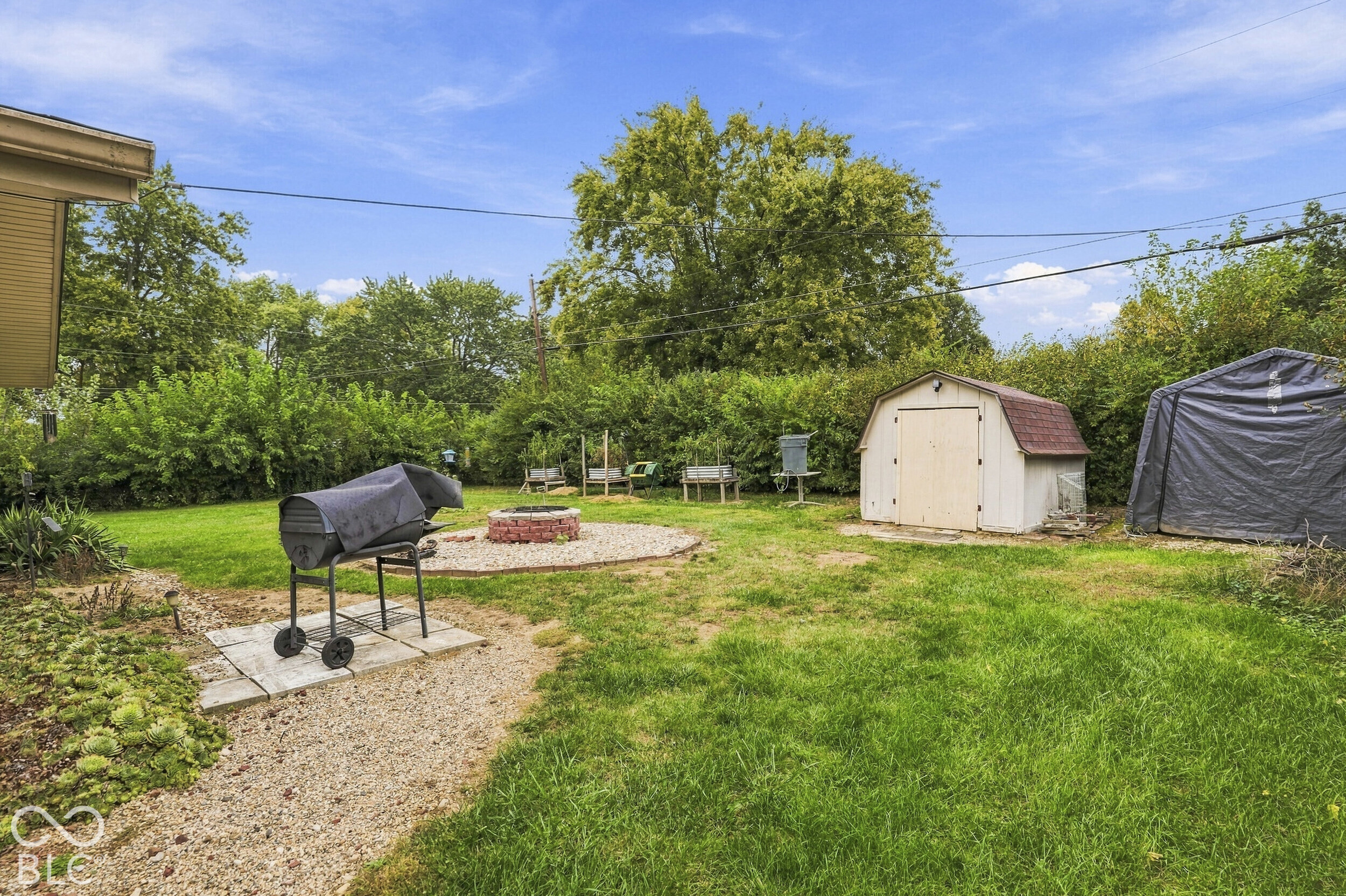 The backyard space features a lawn, a brick-surrounded fire pit, and two storage sheds. The back yard is very private due to the Rose of Sharon bushes.