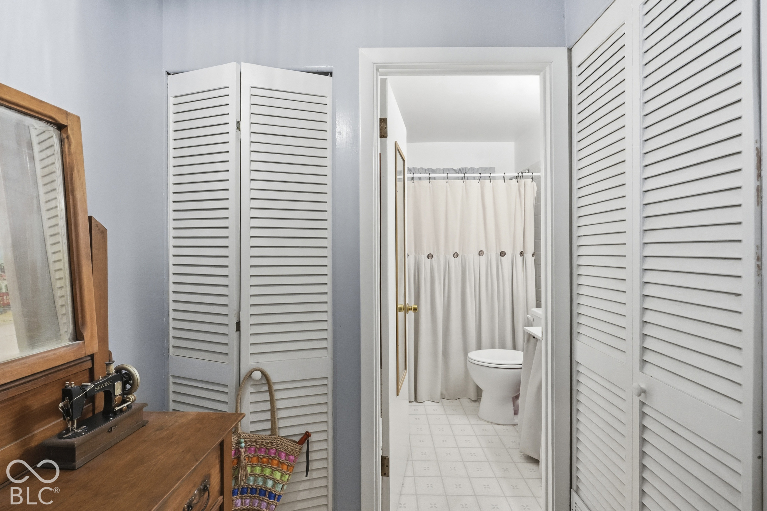 This spacious full bathroom features bi-fold louvered closet doors with white finish and ceramic tile flooring.