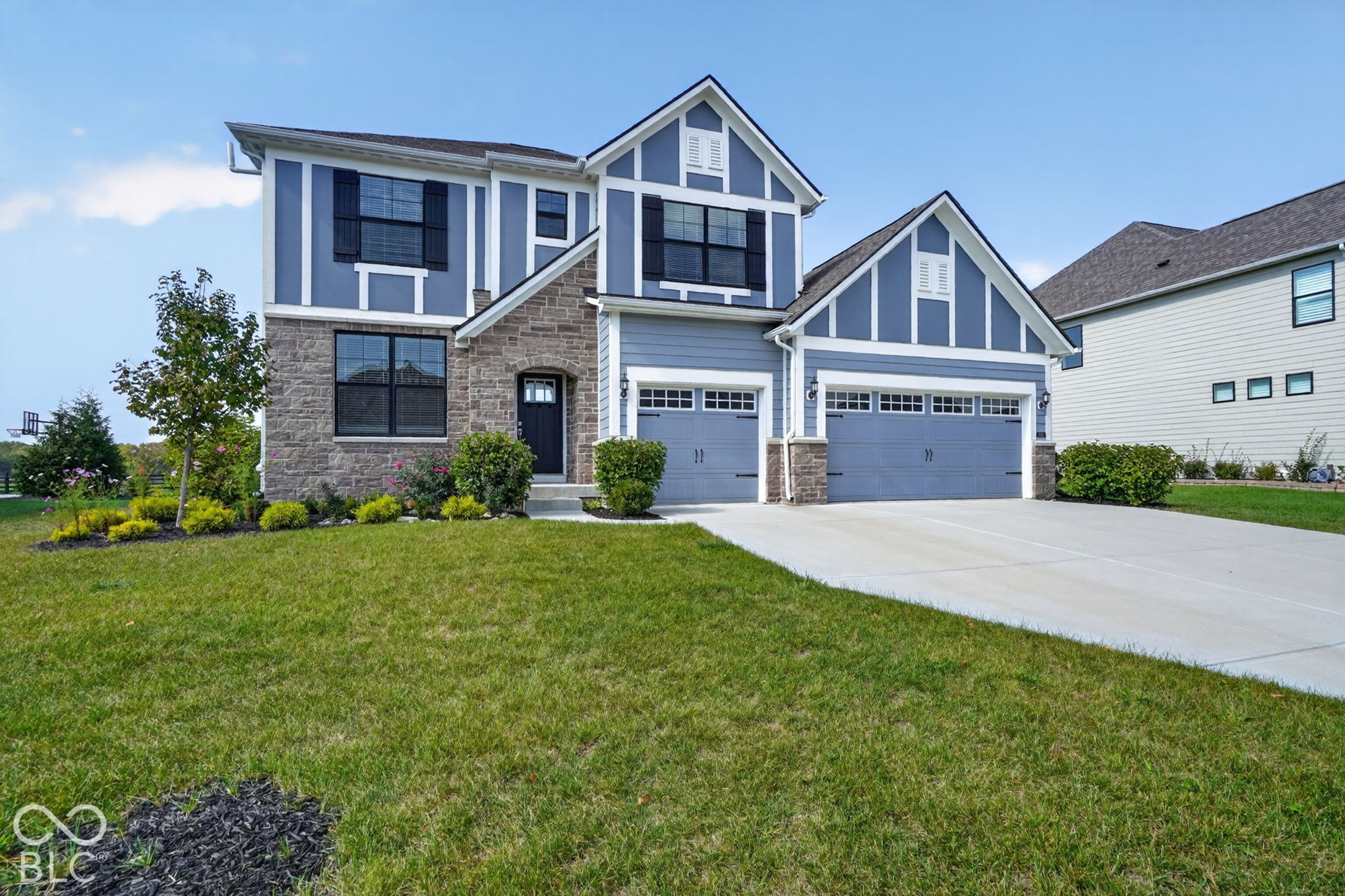 Two-story residence featuring a stone and horizontal siding facade, multiple gables, and an attached three-car garage