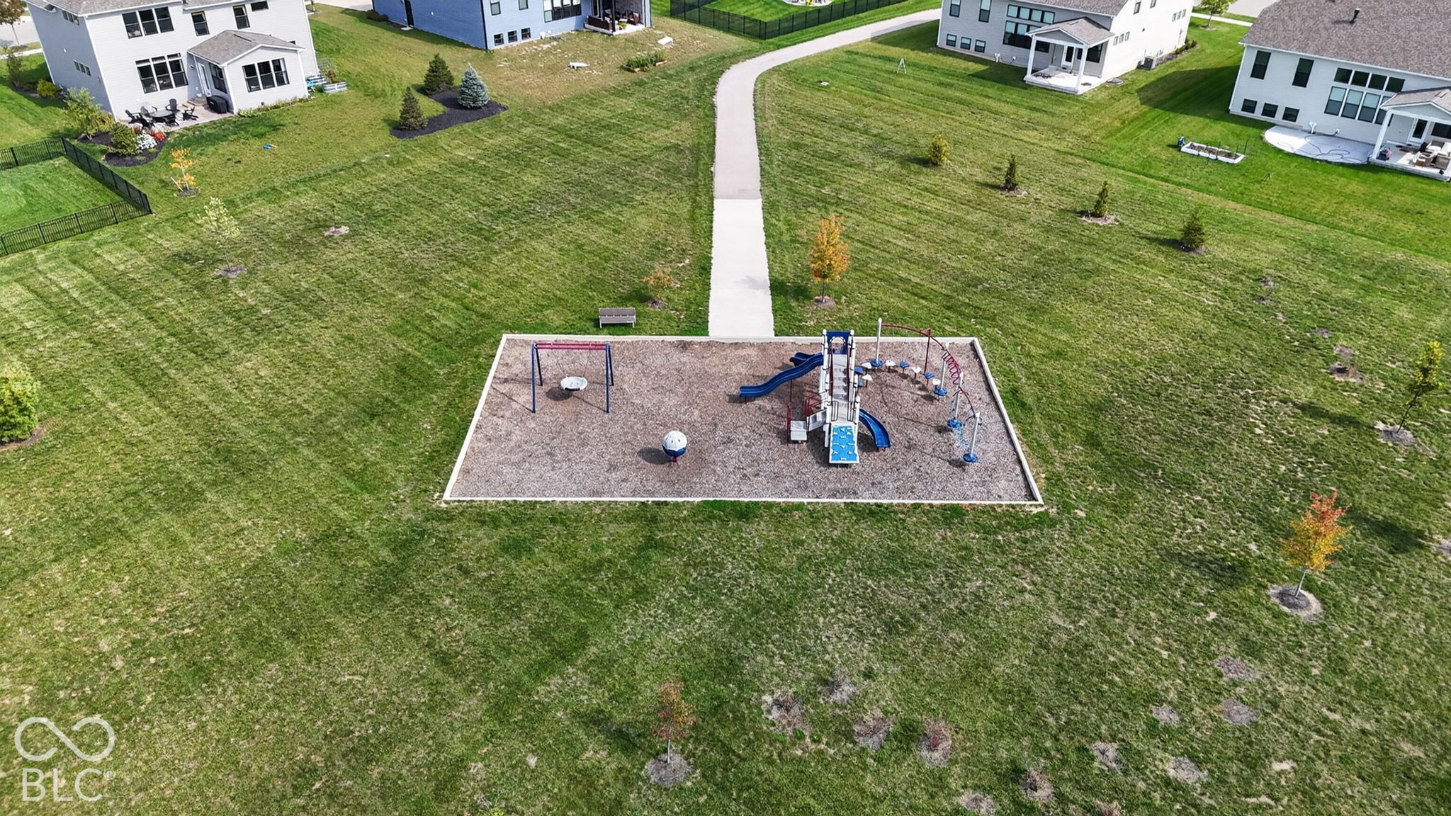 Community green space featuring a playground structure with slides and swings, mulch surfacing, and concrete pathways