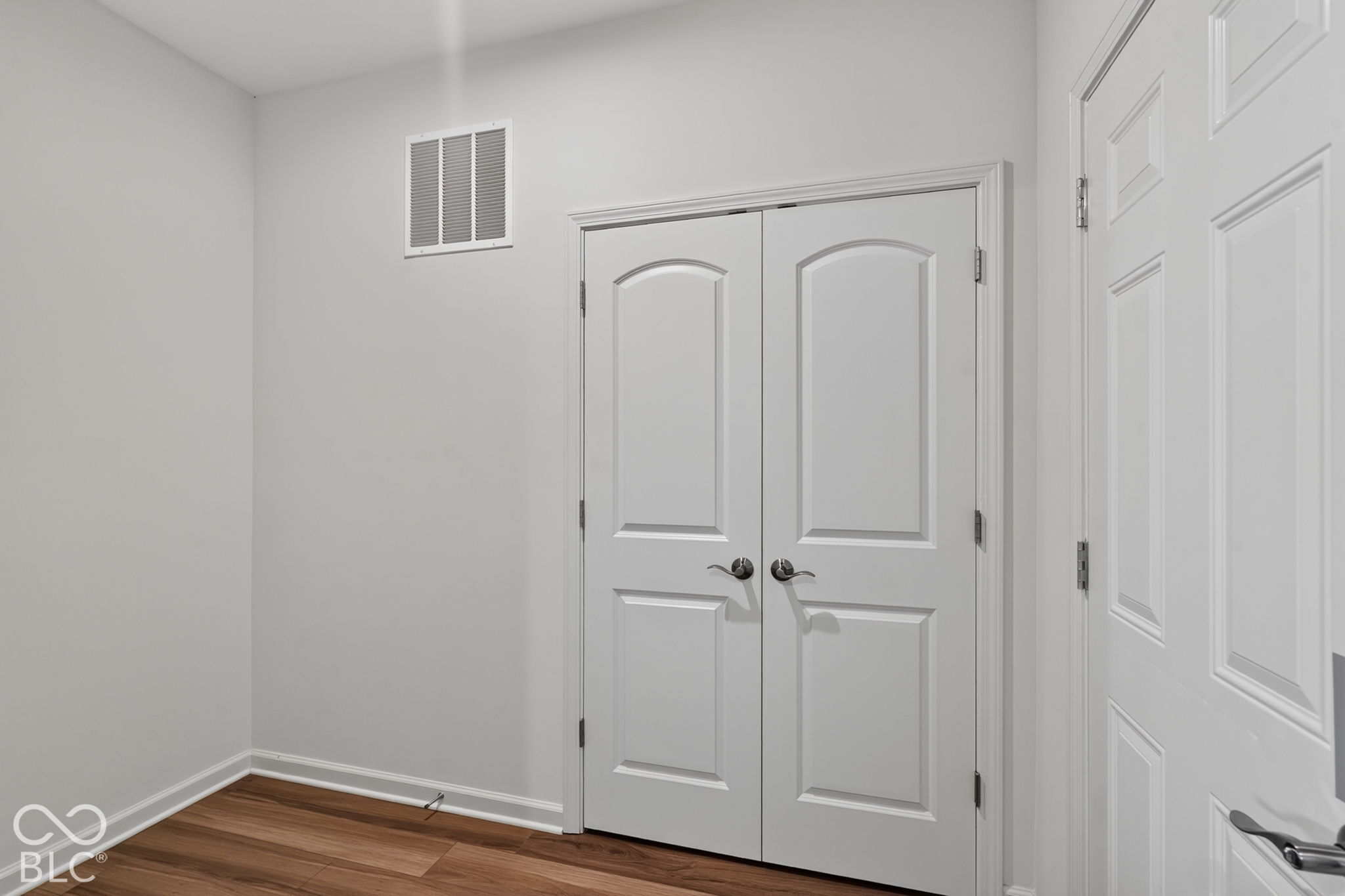 Interior space featuring wood-finish flooring and double-panel arched doors with metallic hardware