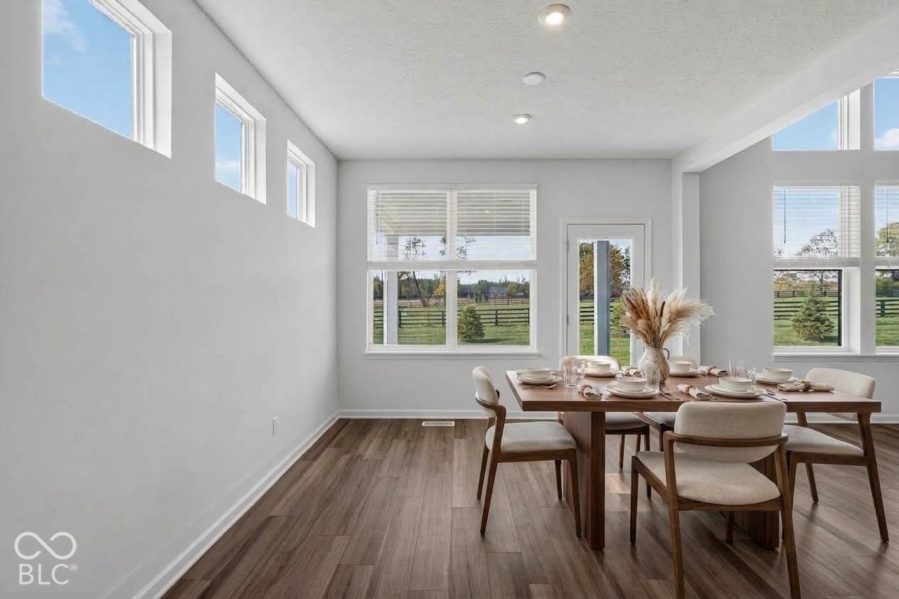 Virtually Altered - High-ceilinged room featuring wood-finish flooring, recessed lighting, expansive multi-pane windows, and a glass-paneled exterior door