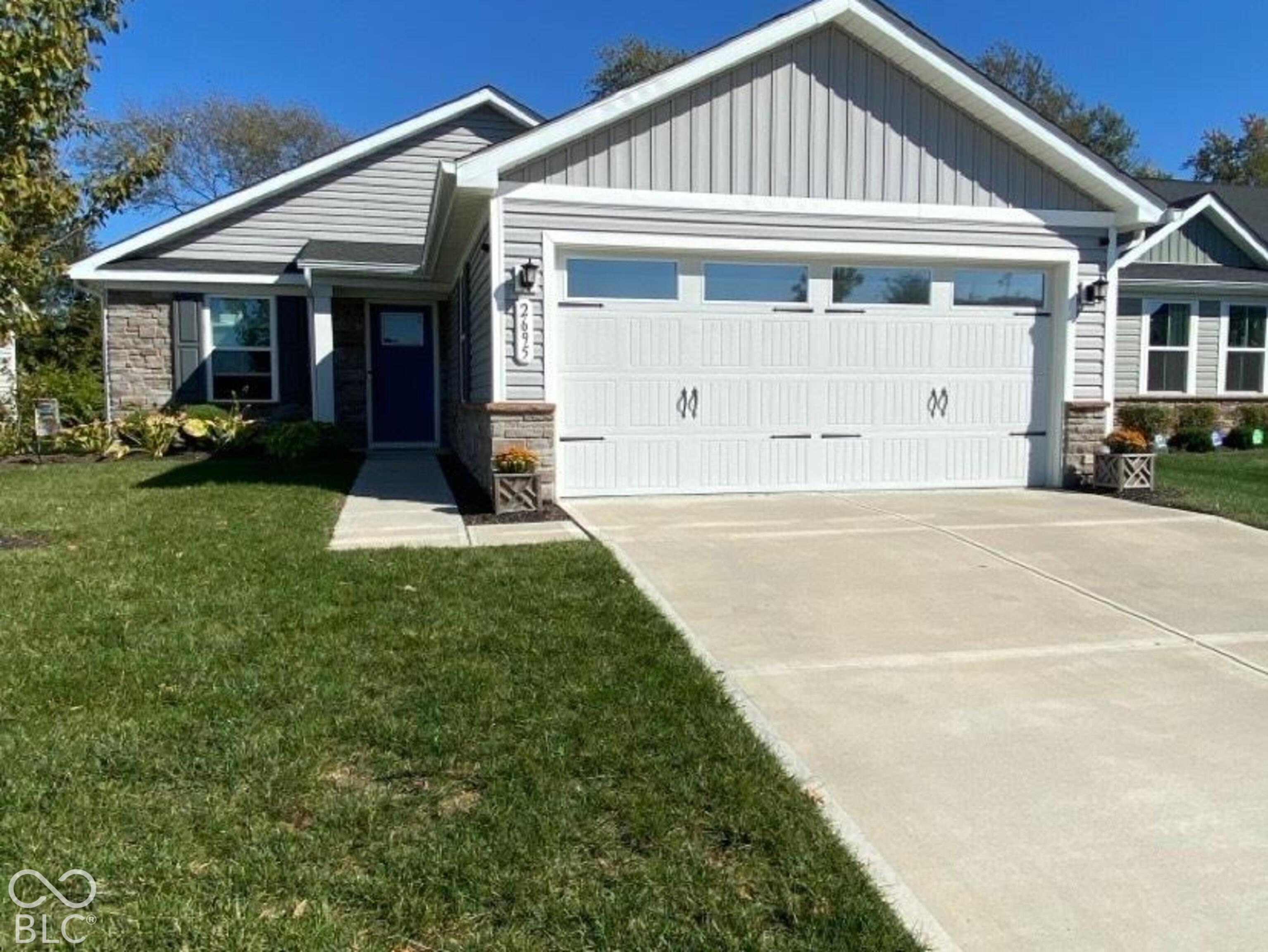 Single-story exterior featuring a stone and horizontal siding facade, a double-car garage with glass paneling, and a concrete driveway