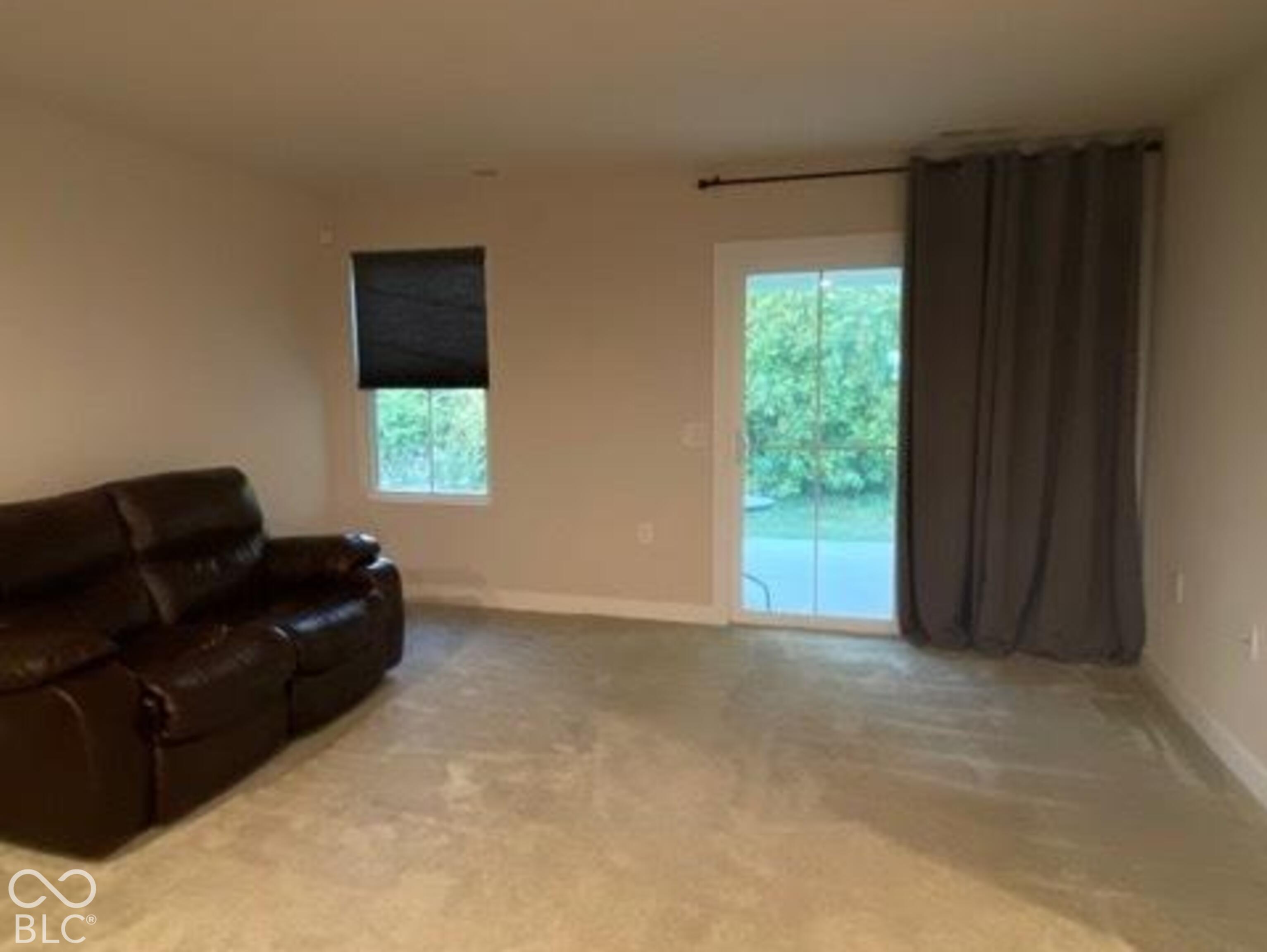 Neutral-toned interior space featuring wall-to-wall carpeting, a single window, and a sliding glass door providing external access