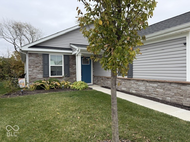 Charming single-story home featuring a brick and vinyl exterior, welcoming blue entry door, and mature landscaping with established trees