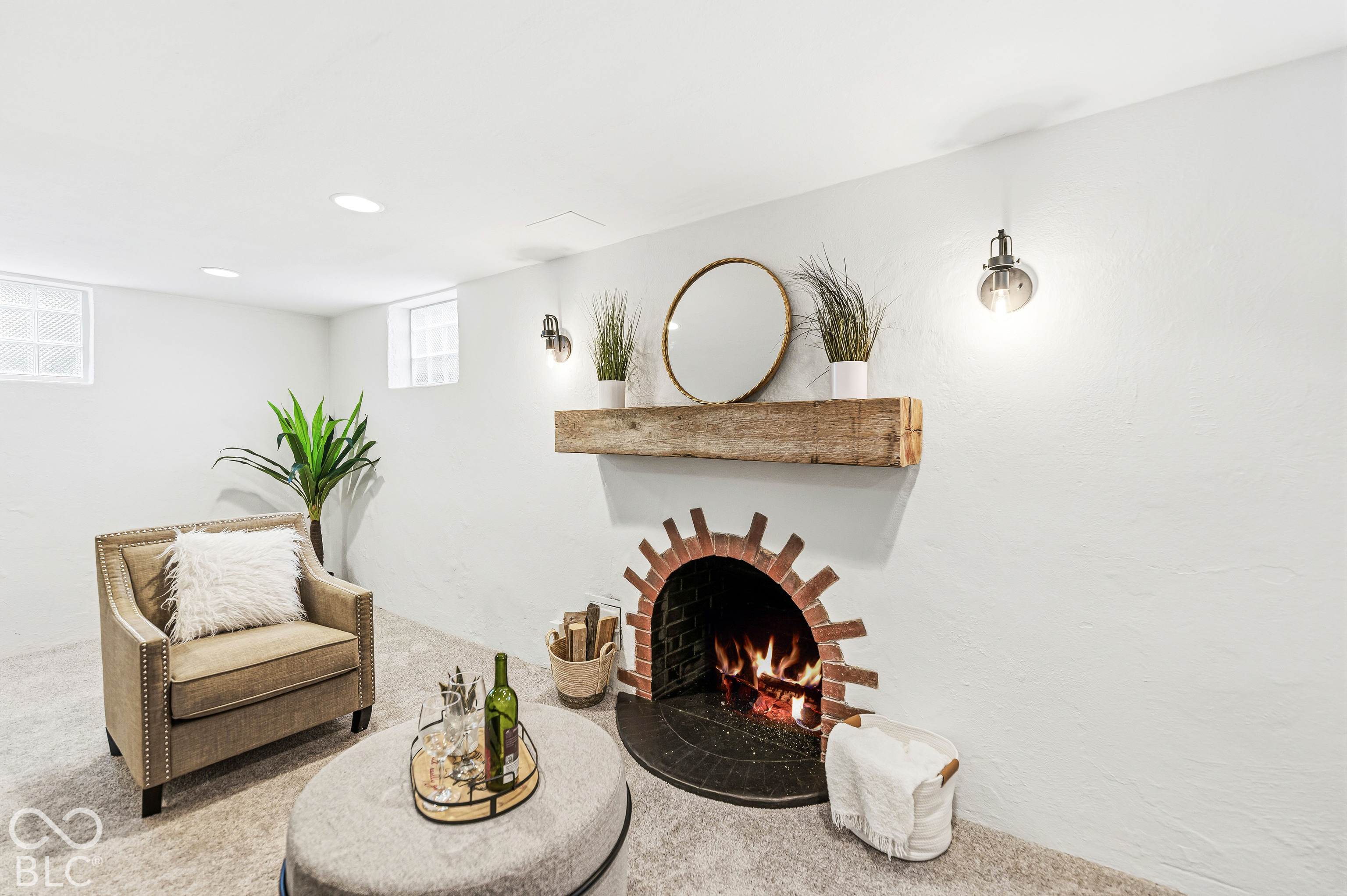 Fireplace with a decorative red brick arched surround, natural stone hearth, and a reclaimed wood mantel, complemented by recessed ceiling lighting and wall-mounted metal sconces