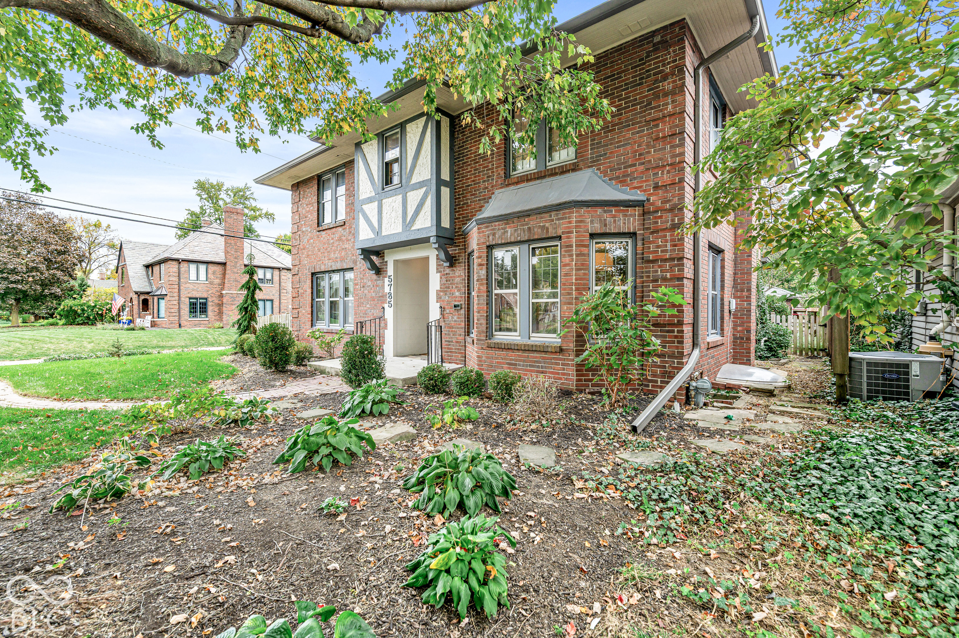 Brick exterior featuring timber-framing details, a bay window, and a recessed entryway with a stone walkway