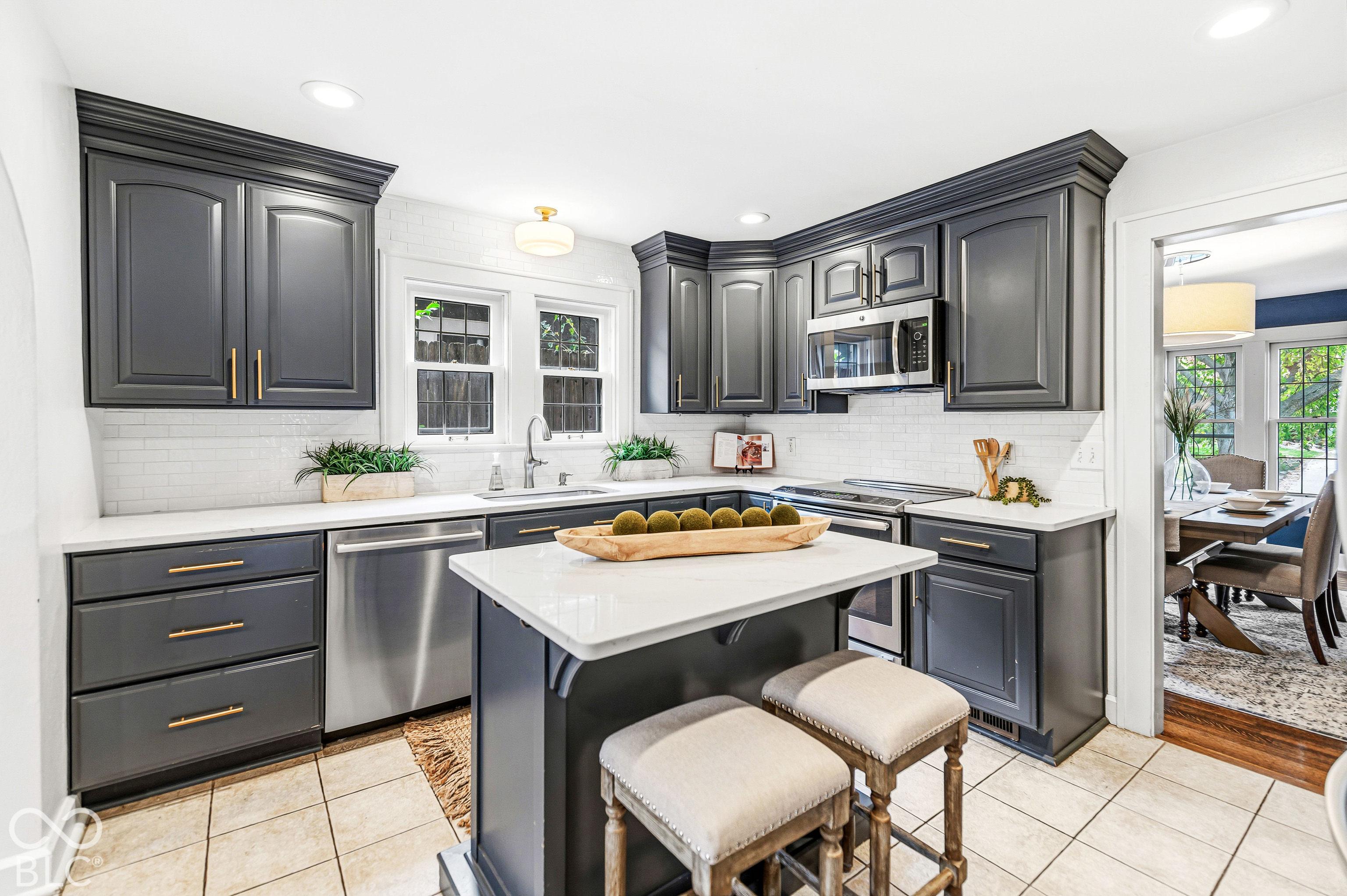 Kitchen featuring dark-toned cabinetry, a central island with quartz surfacing, stainless steel appliances, and subway tile backsplash
