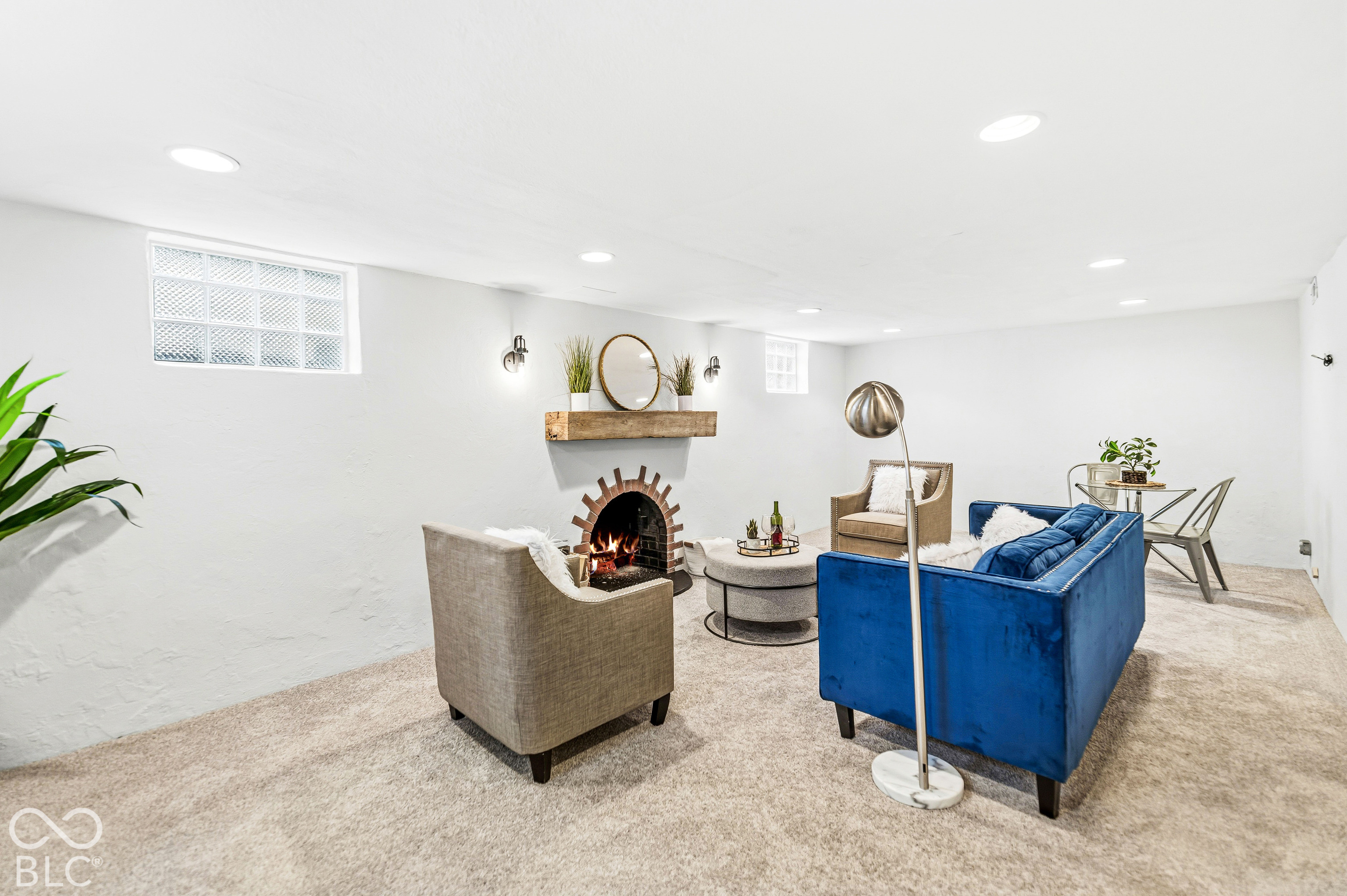 Interior space featuring carpeted flooring, recessed ceiling lighting, glass block windows, and a masonry-style fireplace with a floating wood mantel