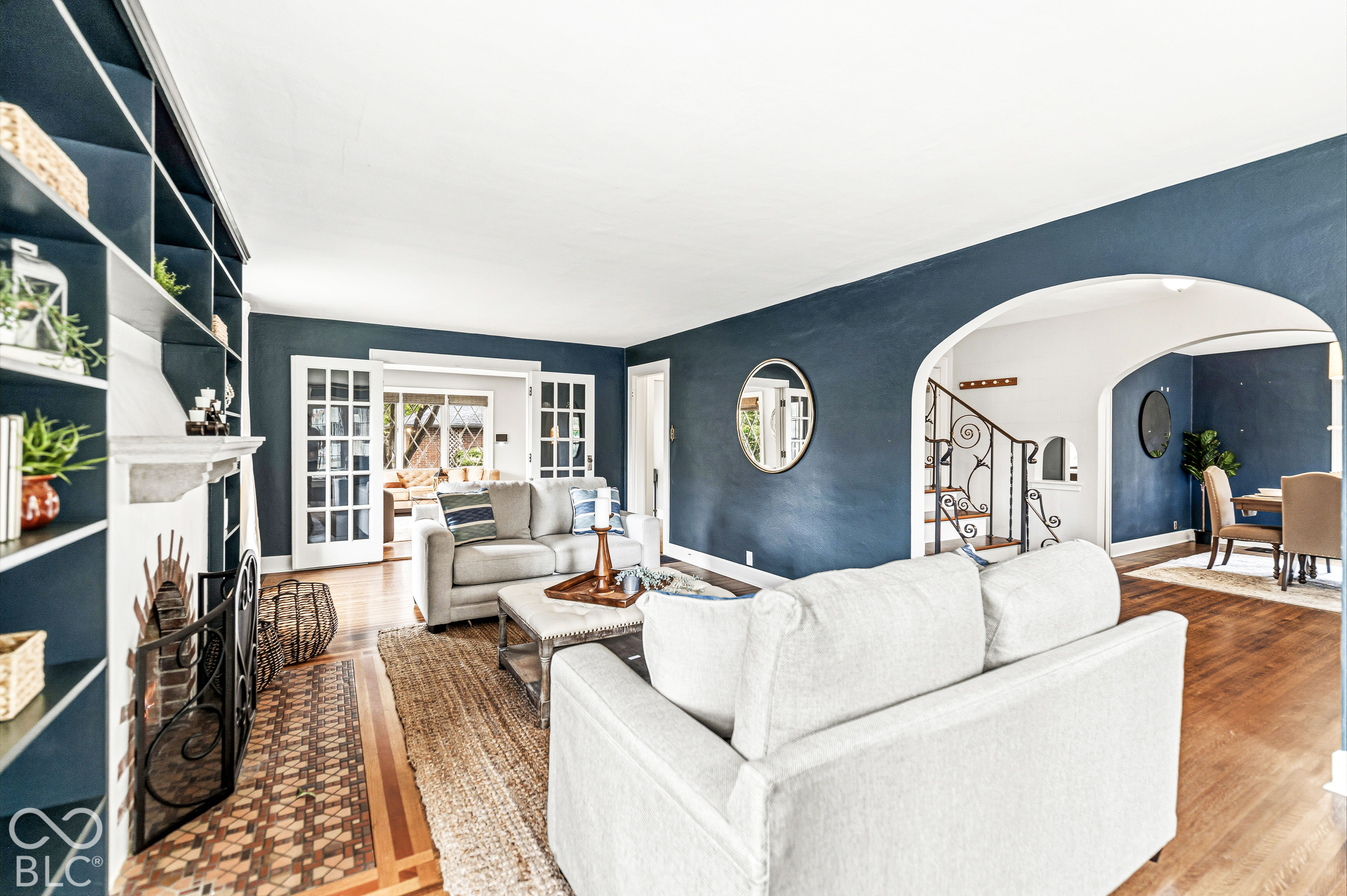 Built-in floor-to-ceiling shelving, masonry fireplace with patterned tile surround, arched entryway, and wood-finish flooring