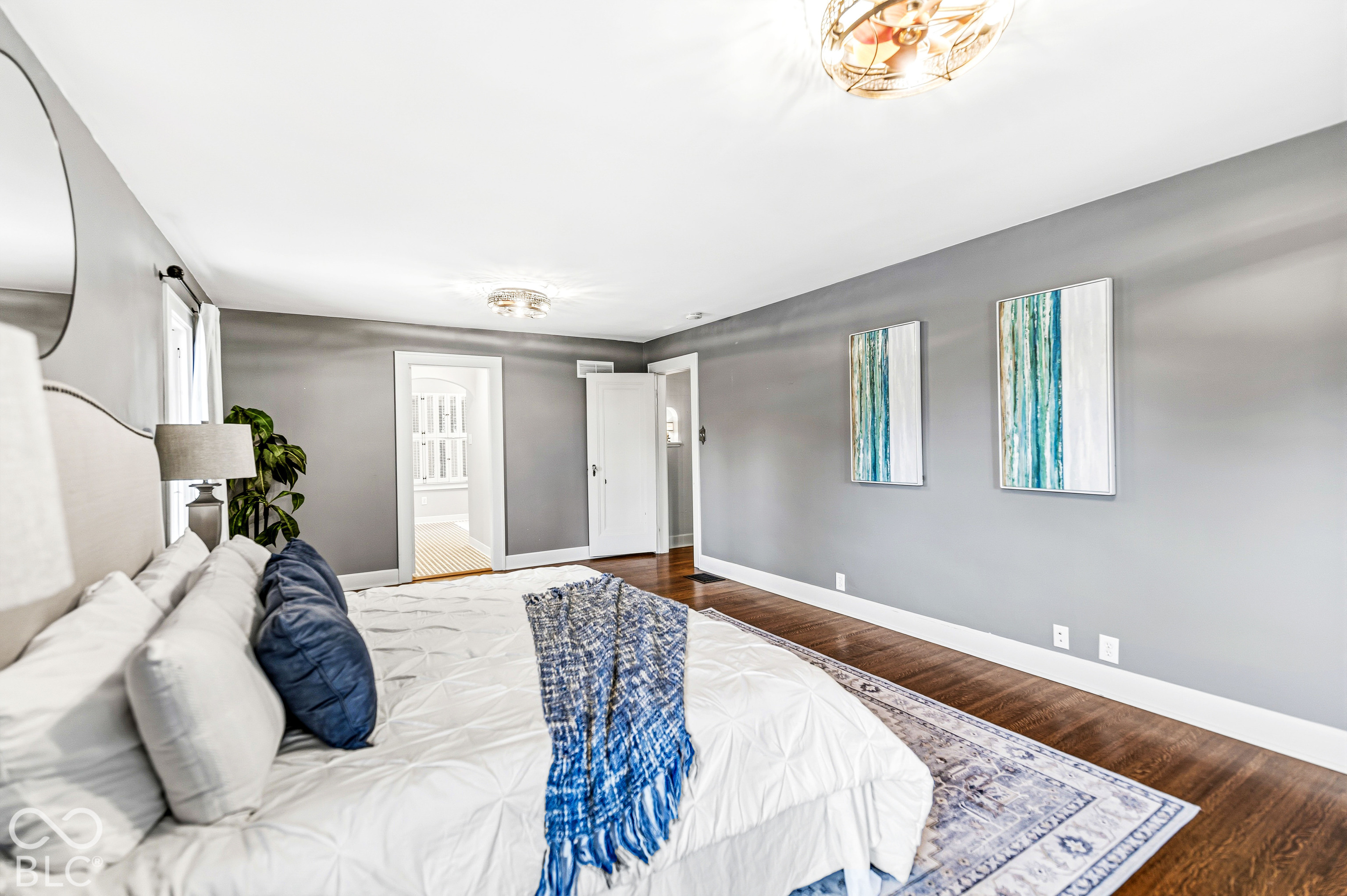 Spacious room featuring wood-finish flooring, neutral wall tones, and two glass-paneled ceiling light fixtures