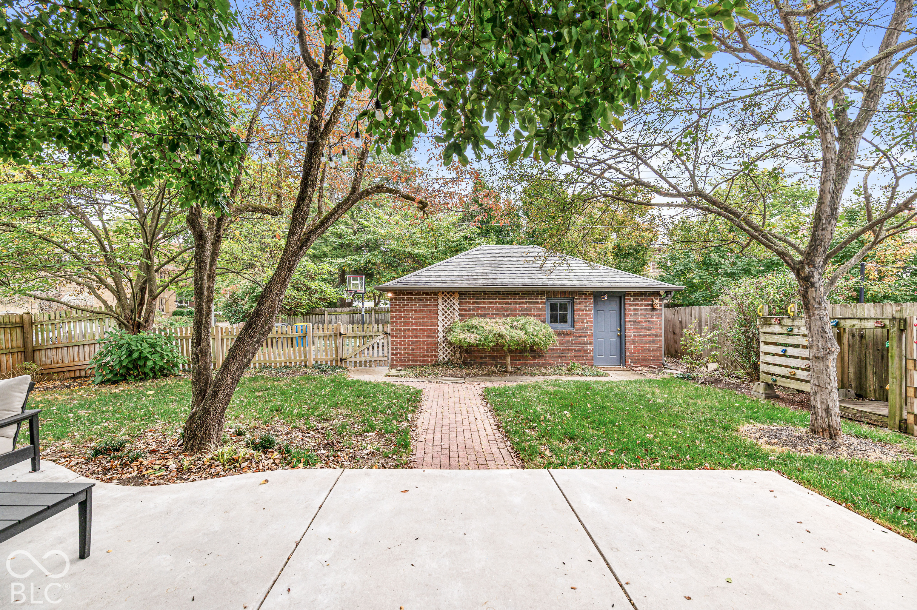 Backyard featuring a brick-exterior detached garage, paved patio, brick walkway, and perimeter wood fencing