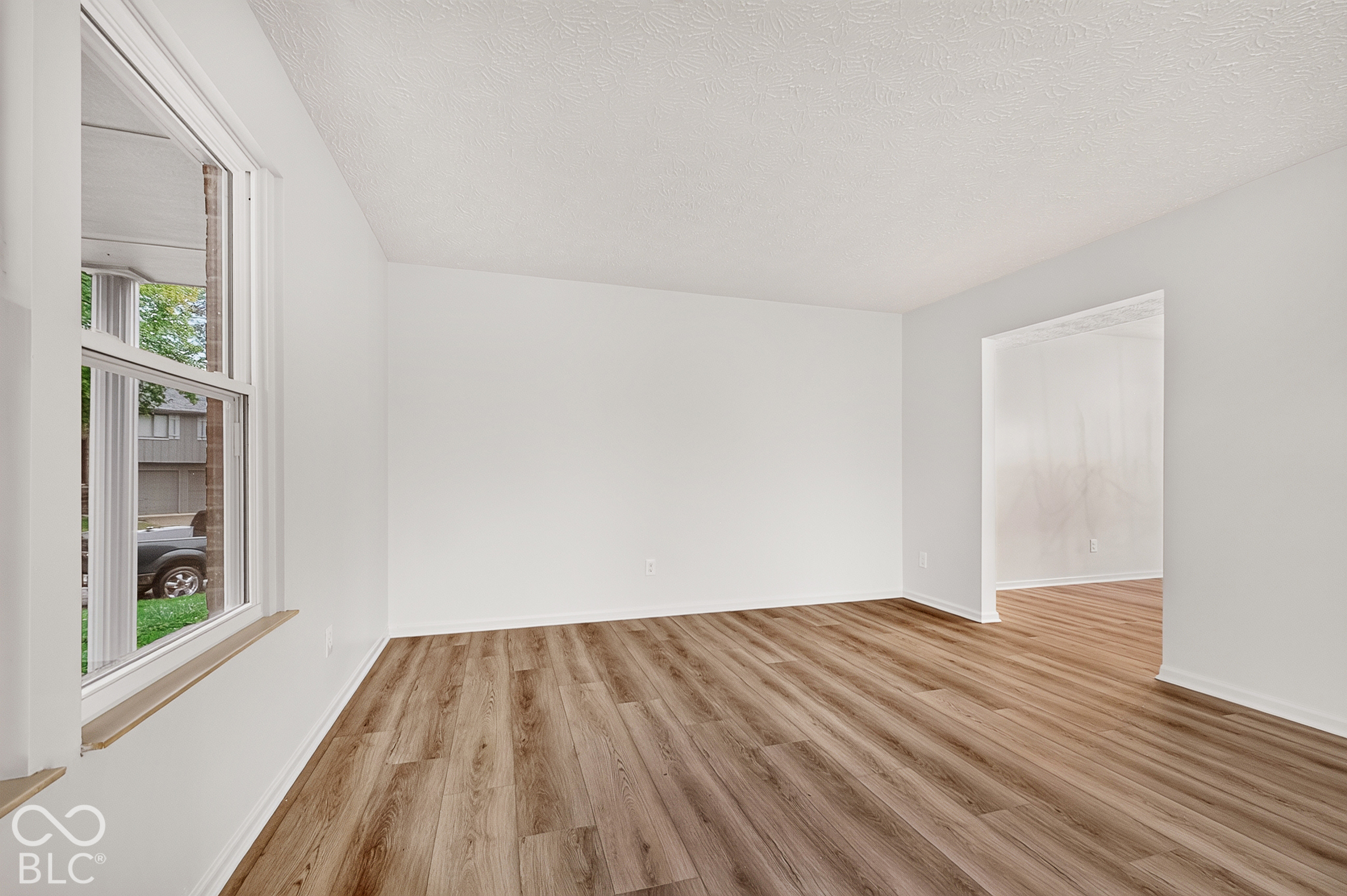 Neutral wall finishes, wood-finish flooring, and single-hung window with a wooden sill