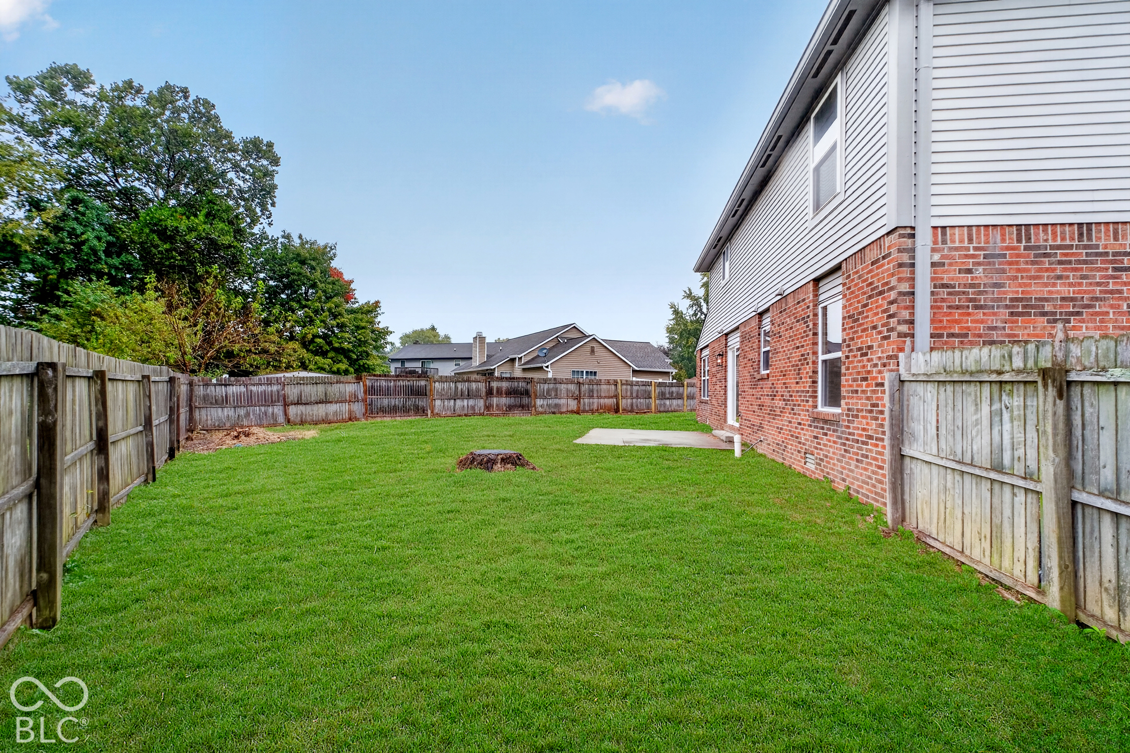 Private backyard featuring a grass lawn, a concrete patio, and wood privacy fencing