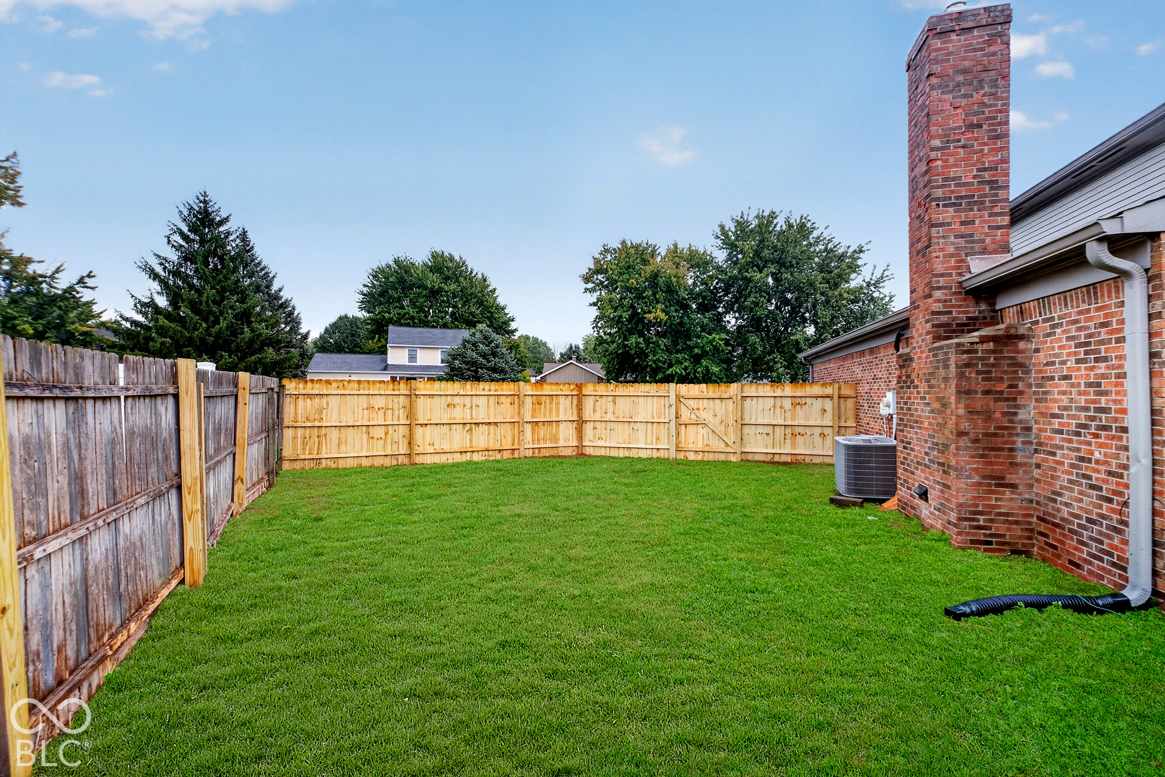 Private backyard featuring a manicured lawn, full wood fencing, and an exposed brick chimney