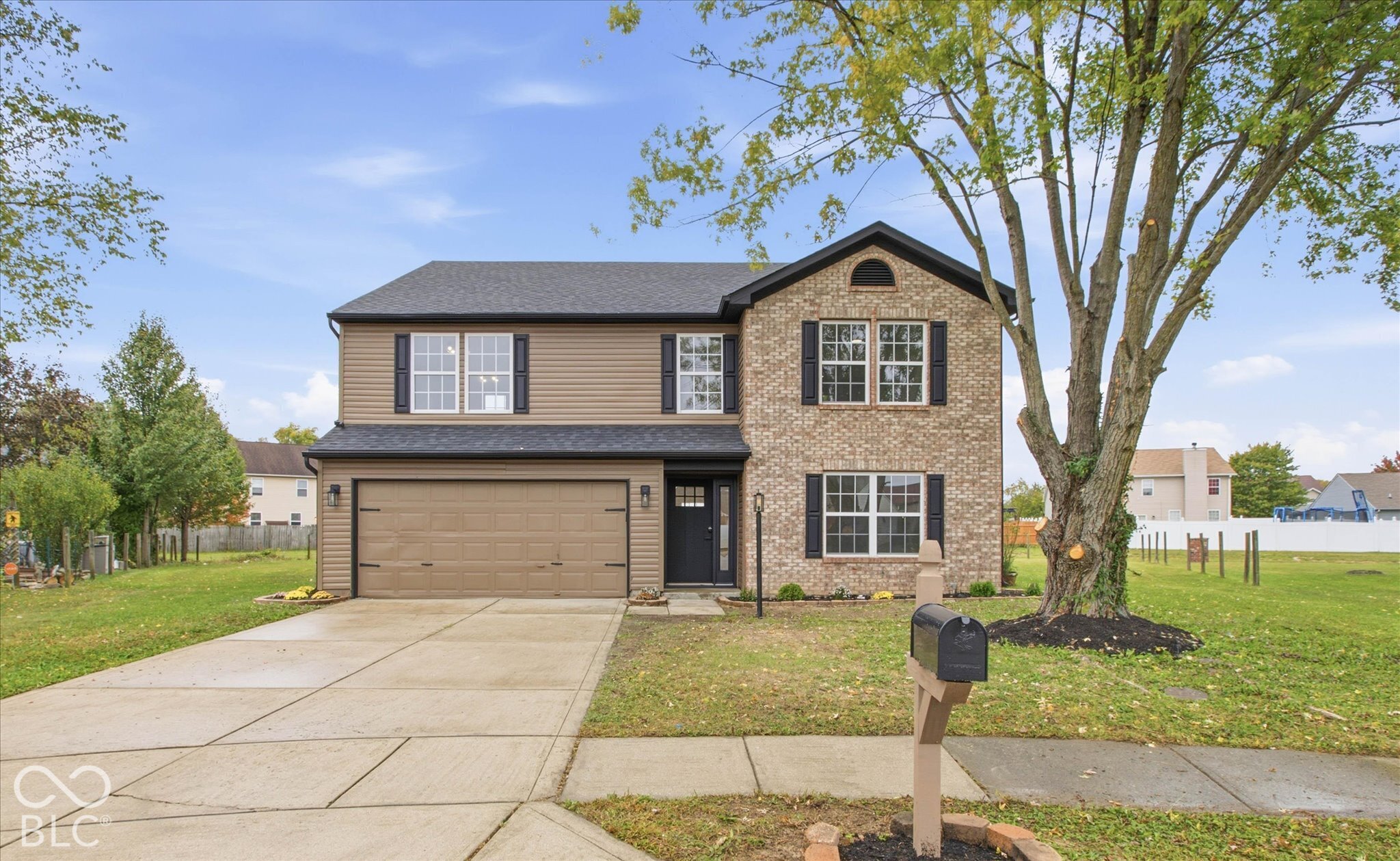 Two-story exterior featuring a brick and horizontal siding facade, asphalt shingle roof, attached two-car garage, and concrete driveway