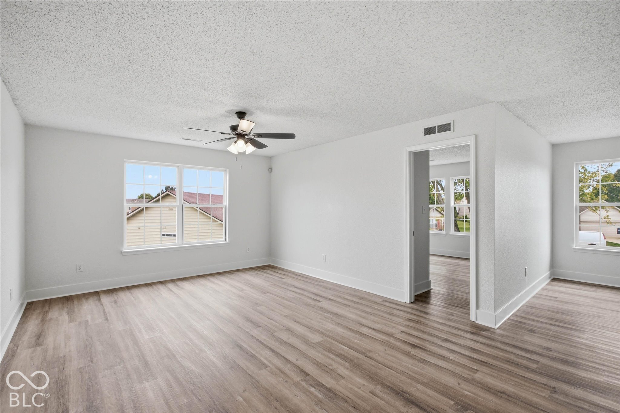 Neutral interior featuring wood-finish flooring, multi-pane windows, and a ceiling fan with integrated lighting