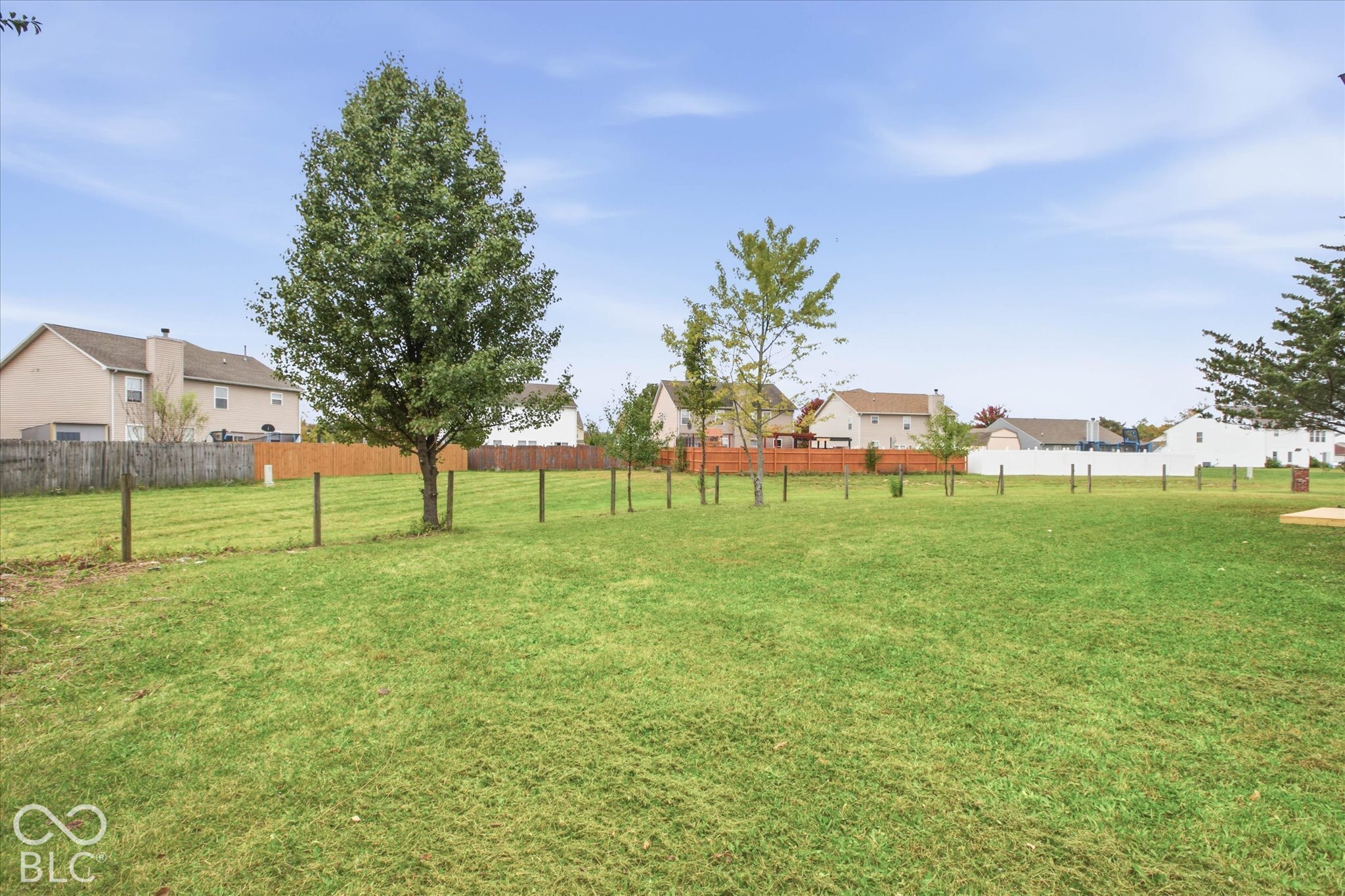 Expansive backyard featuring a level lawn, mature trees, and perimeter fencing