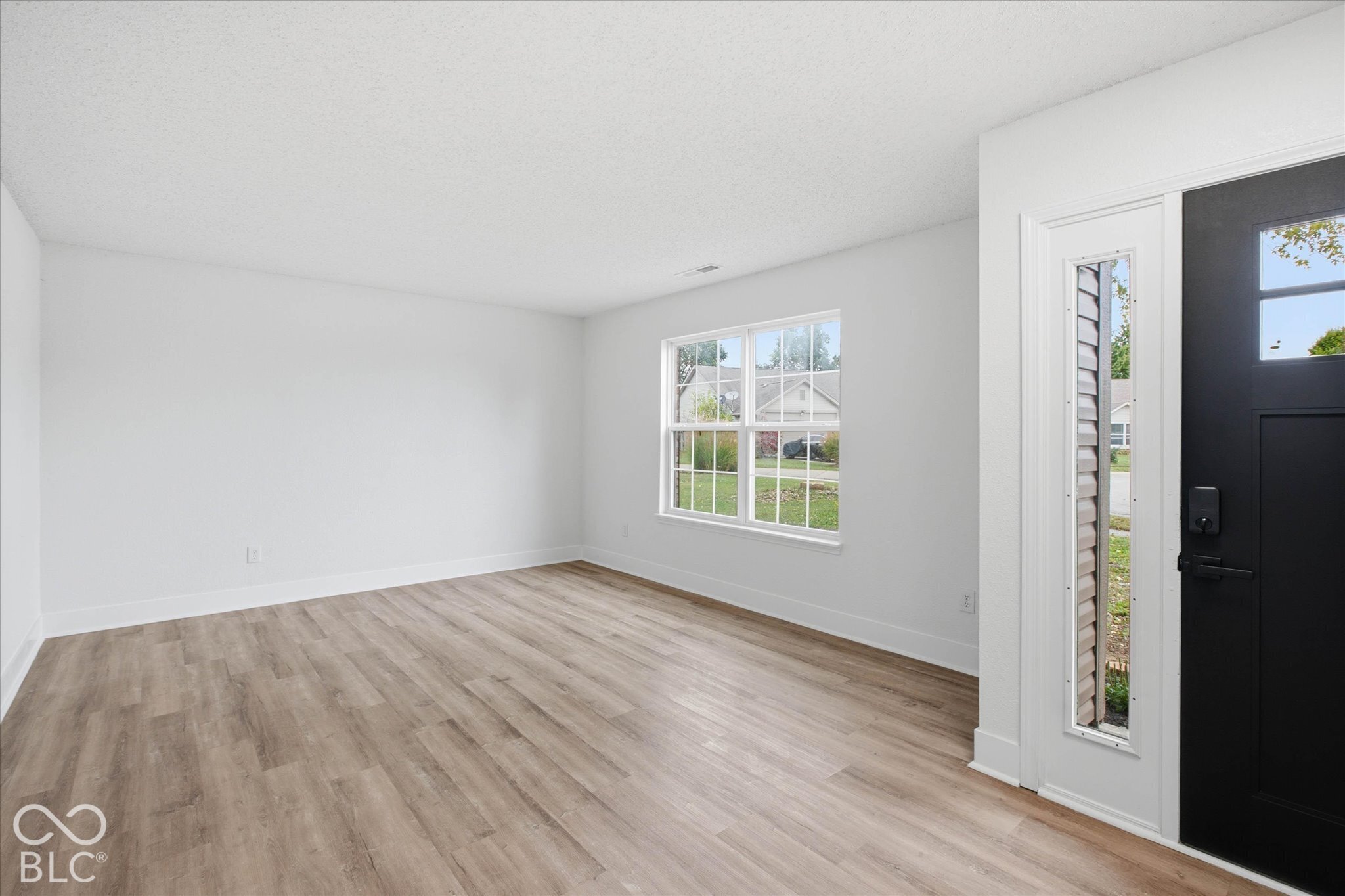 Neutral-toned wall finish, wood-finish flooring, multi-pane window, and exterior door with a vertical glass insert