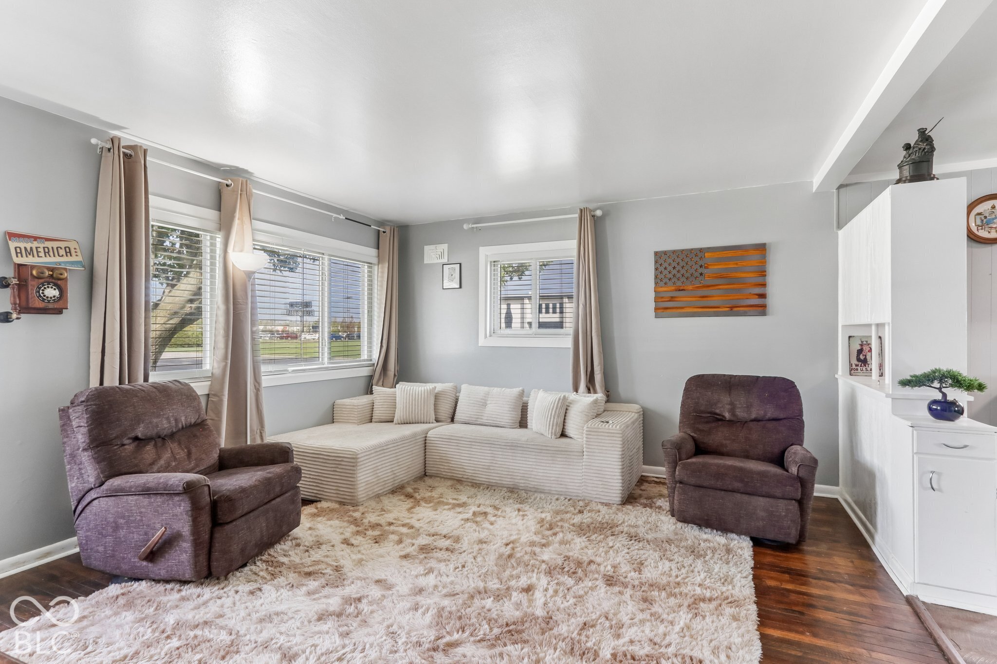 Living area featuring wood-finish flooring, multi-pane windows, and built-in white cabinetry with a partition wall