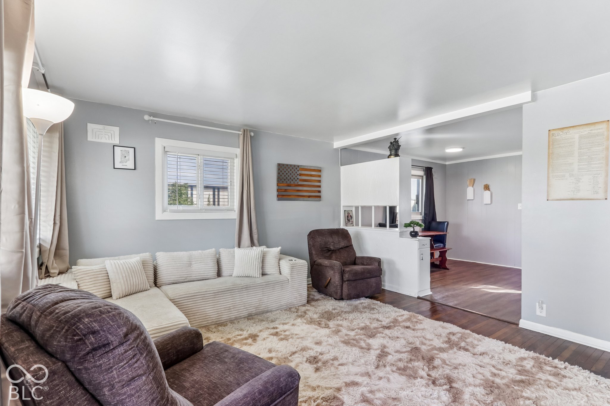 Living area featuring neutral wall paint, wood-finish flooring, and a half-height partition wall with built-in lower cabinetry