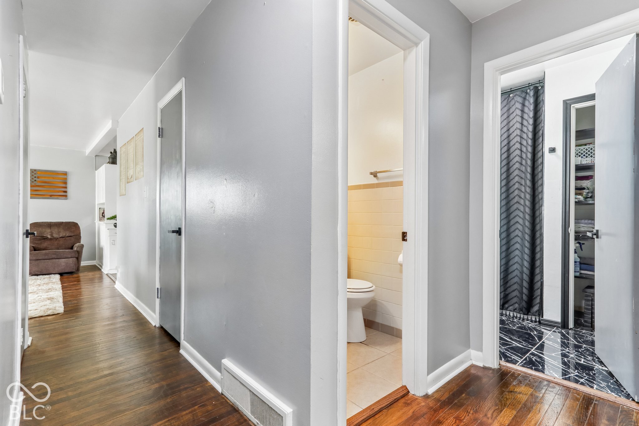 Hallway featuring wood-finish flooring, neutral wall paint, and multiple interior doorways