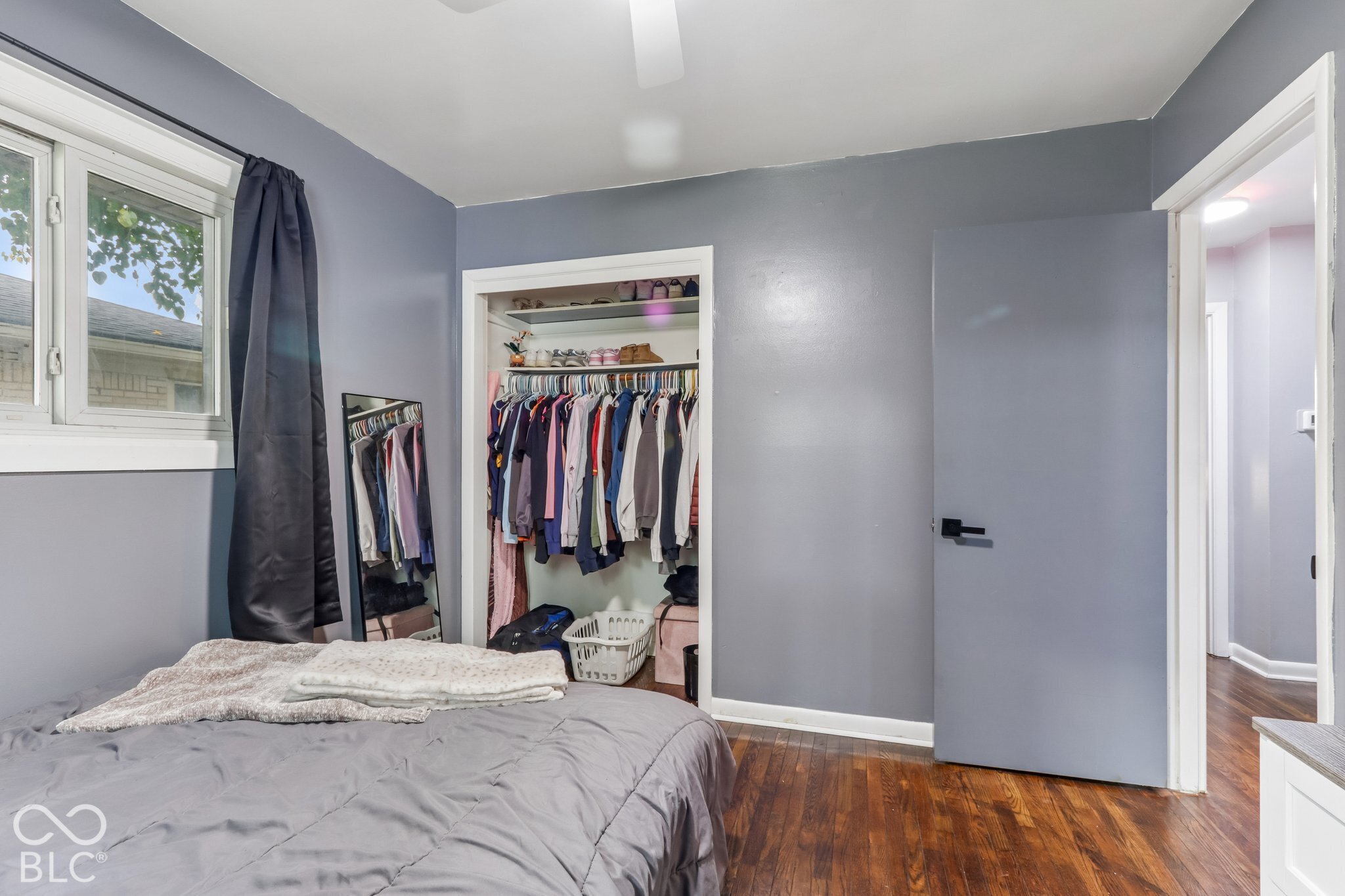 Wood-finish flooring, closet with built-in shelving, solid-core door with matte black hardware, and dual-pane window