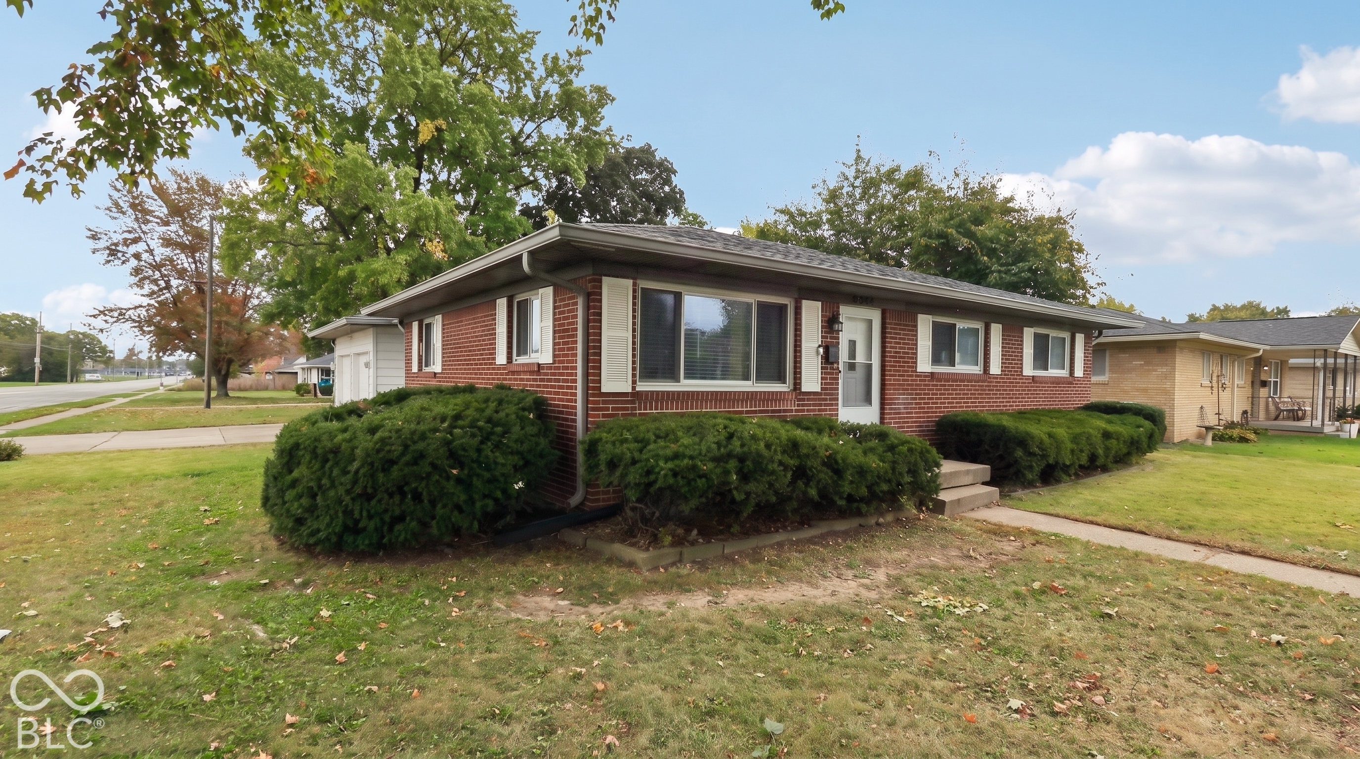 Single-story brick exterior featuring white shutter accents, a low-pitch roof, and a detached garage
